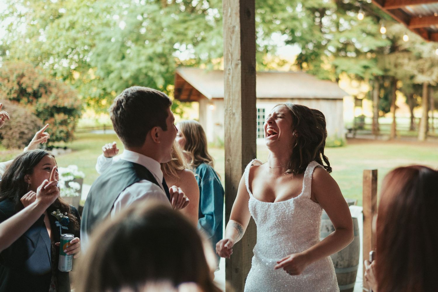 Dancing and laughter during wedding reception under covered outdoor venue.