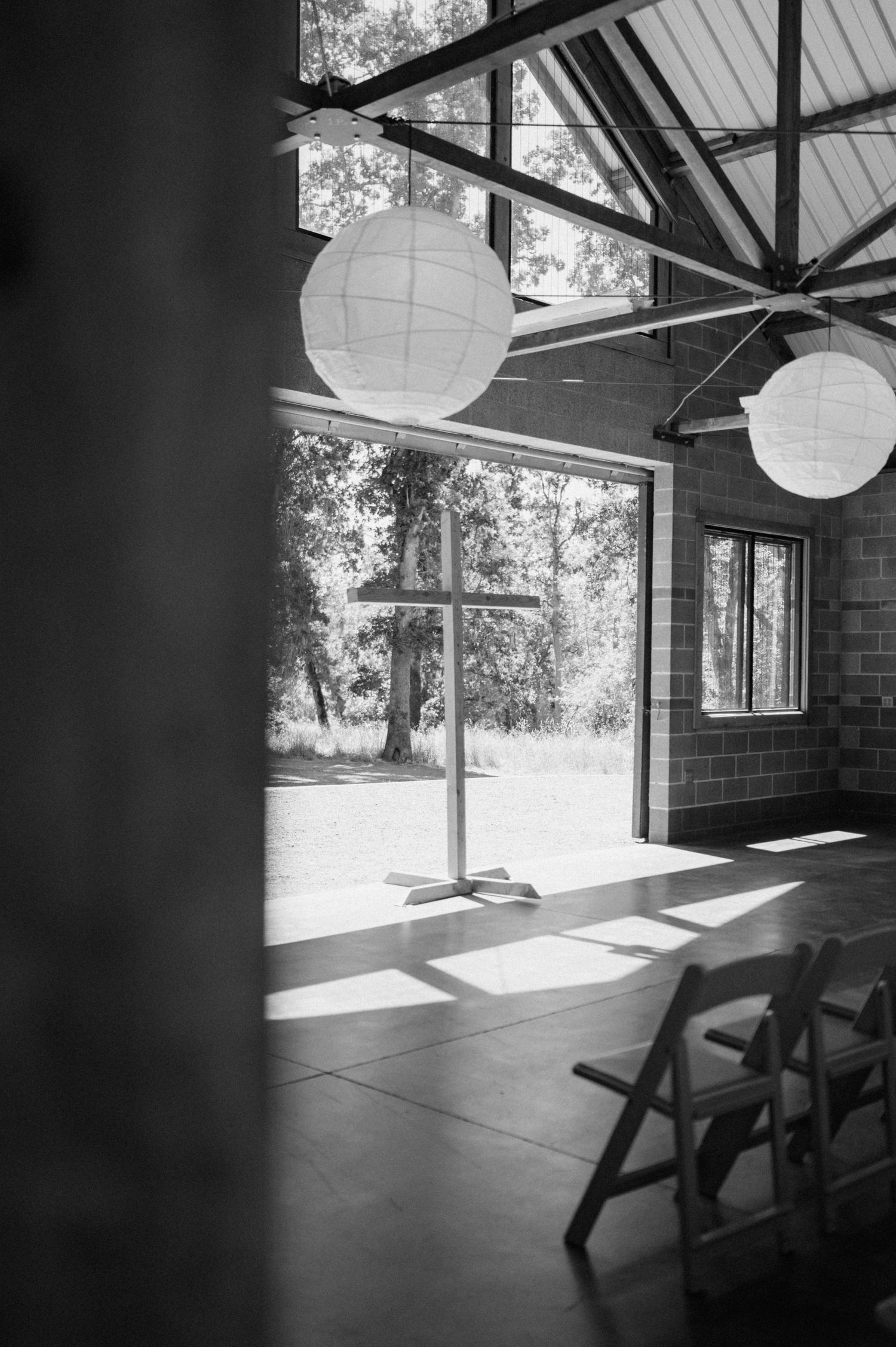 Black and white interior views of a modern cabin with large windows, wooden beams, and hanging paper lanterns.