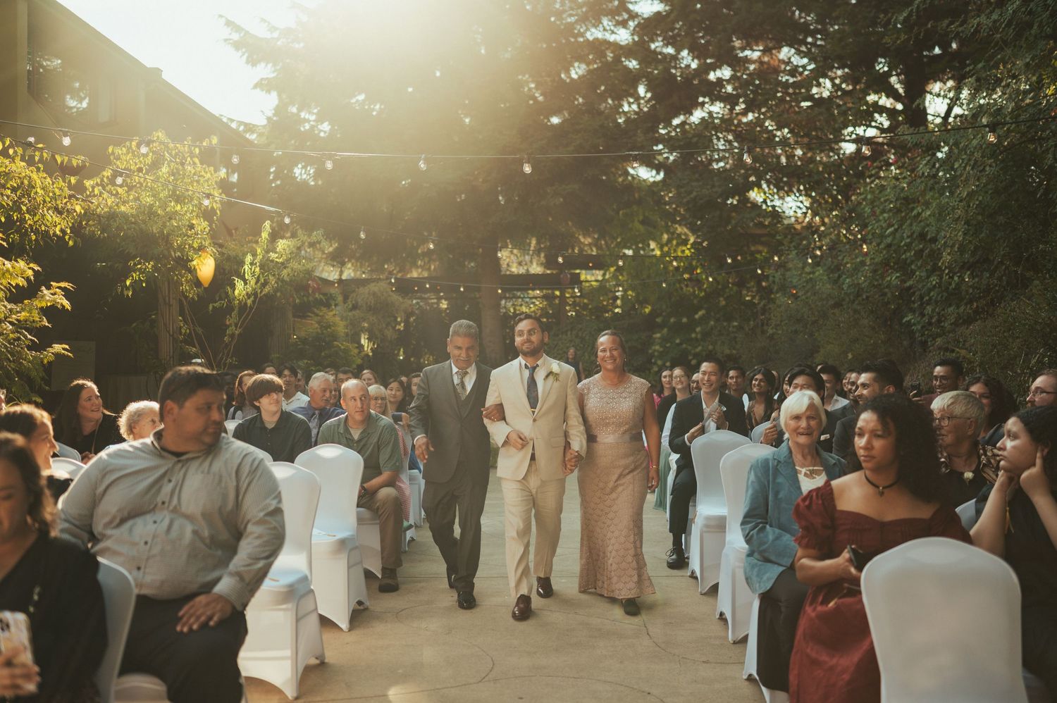 Wedding guests mingle outdoors during golden hour at a sunset garden reception celebration.