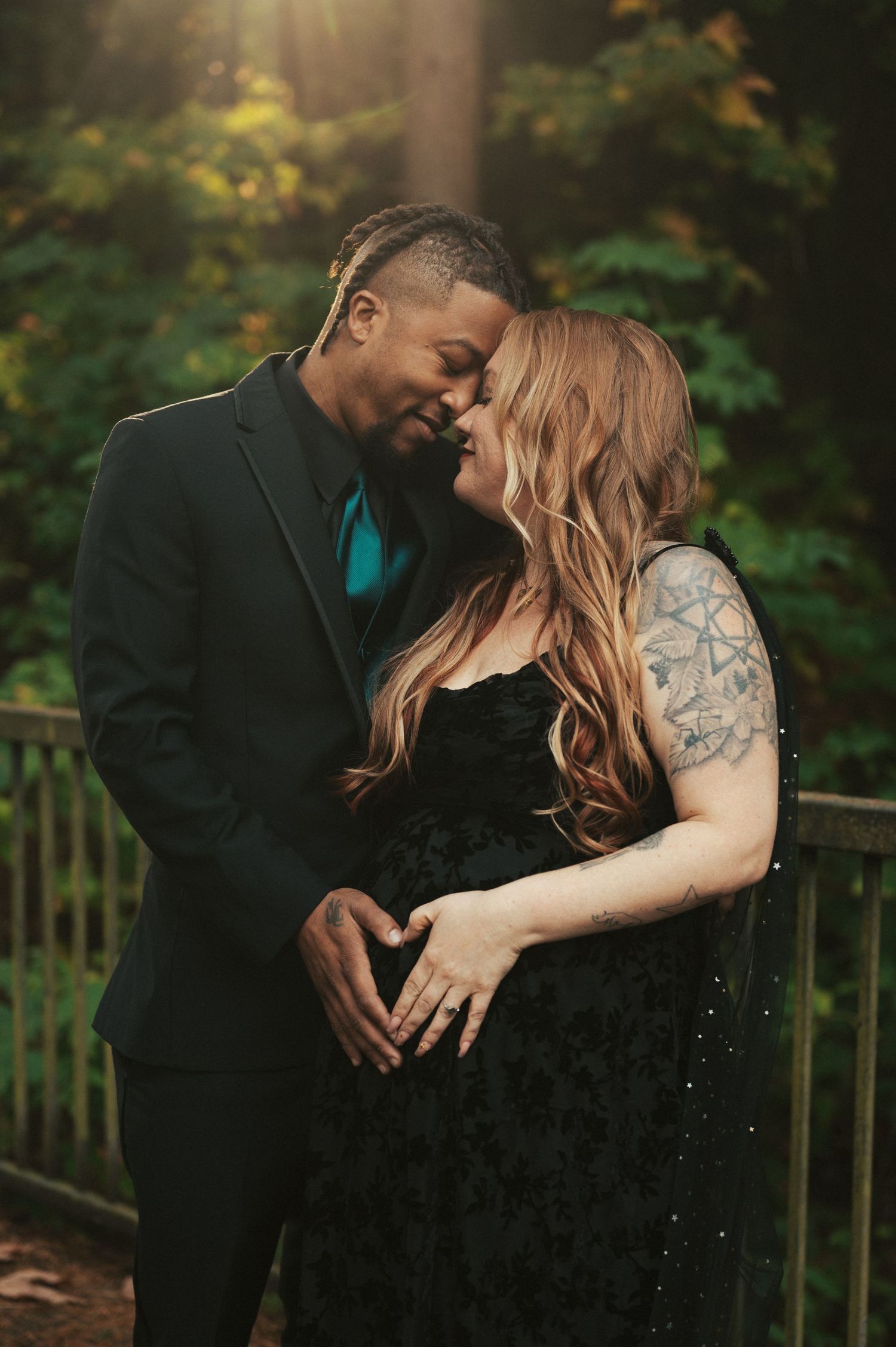 A tender engagement photo of a couple in formal attire sharing an intimate moment in a garden setting.