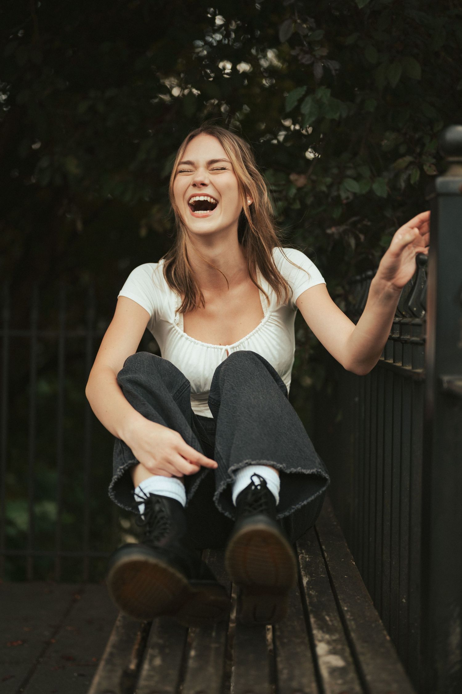 Someone laughing while sitting casually on outdoor steps in dark clothing.