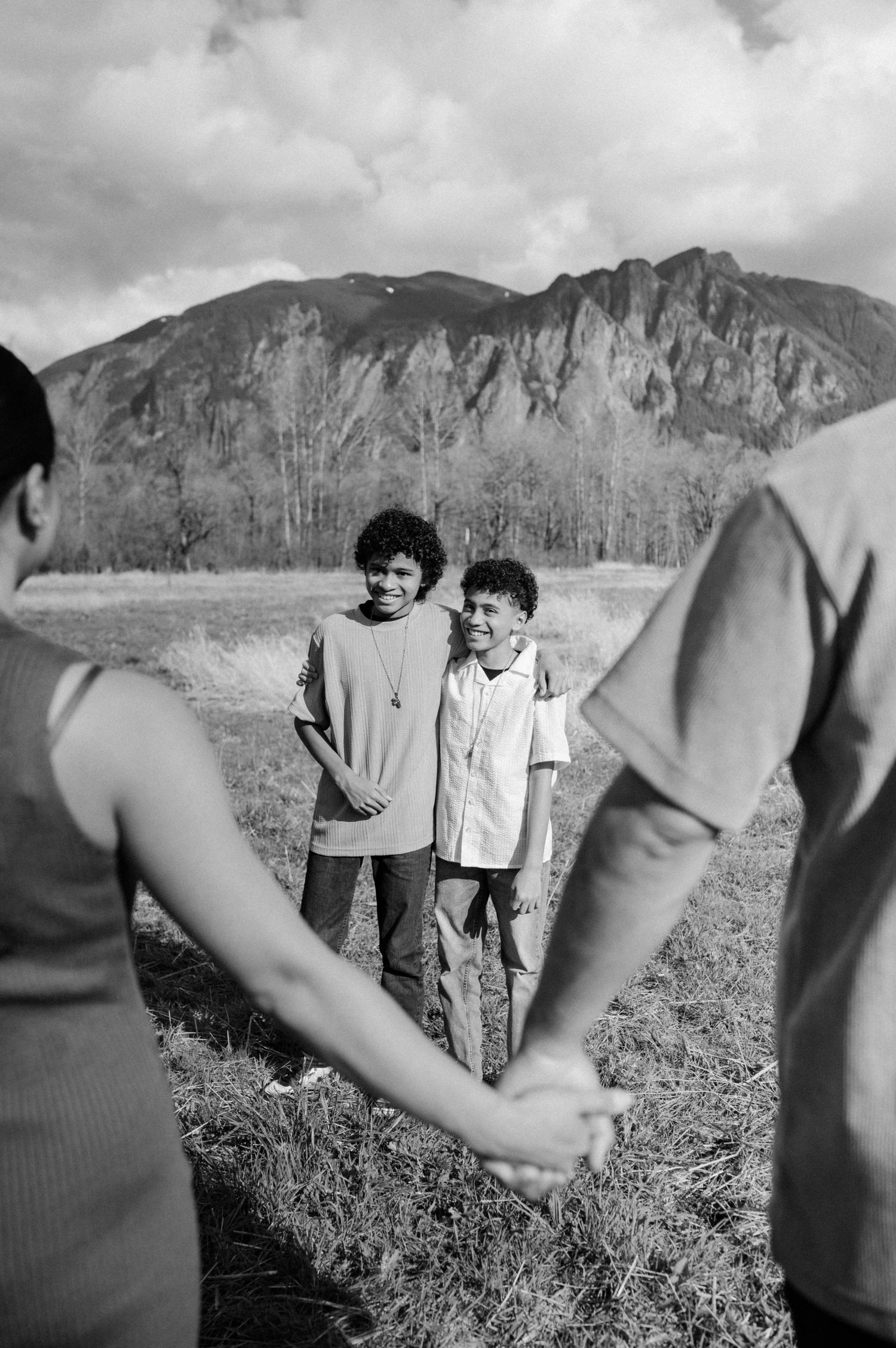 Black and white capture of people walking together in a field with majestic mountain backdrop.