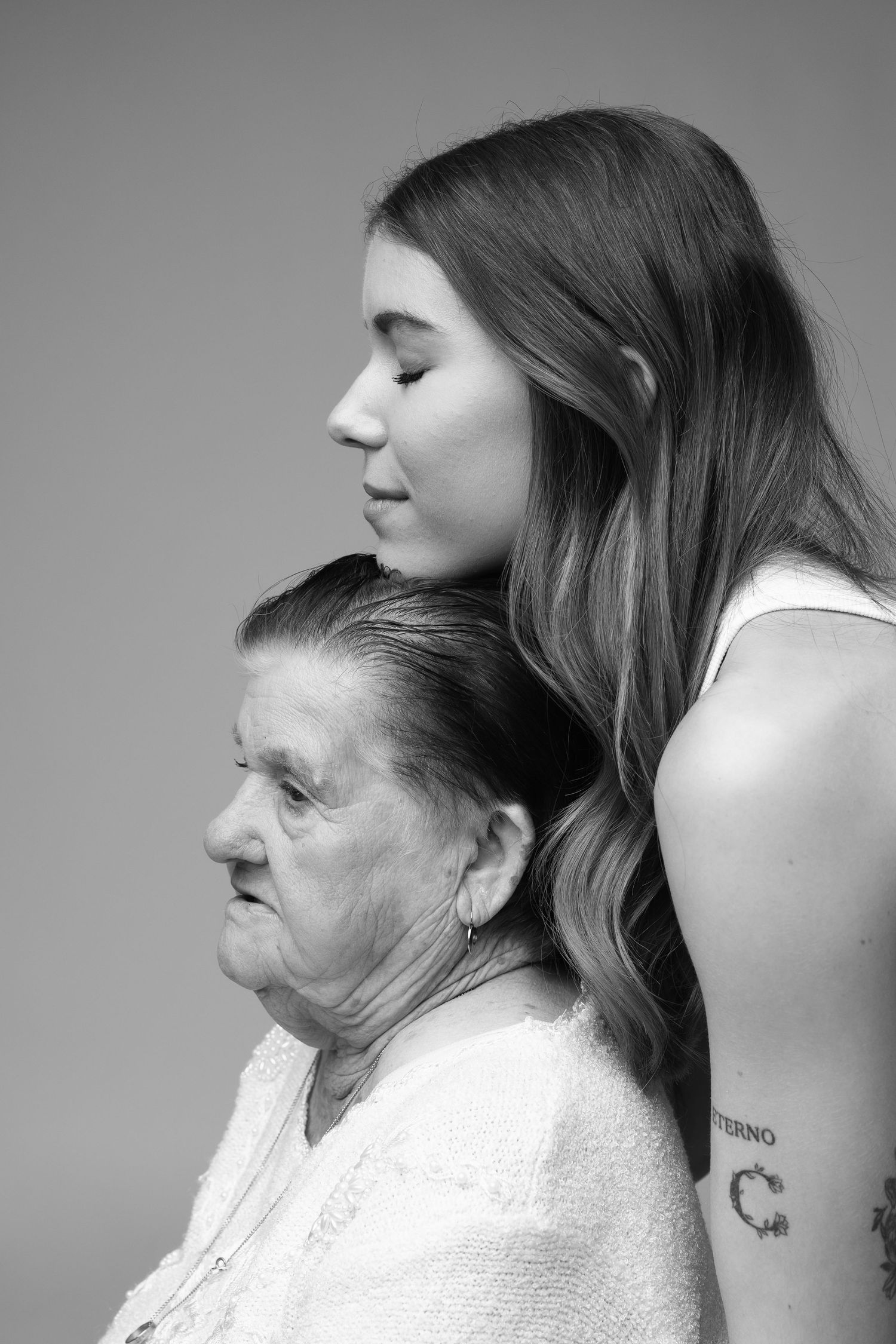 Black and white side profile portrait of elderly woman and young woman together in studio.