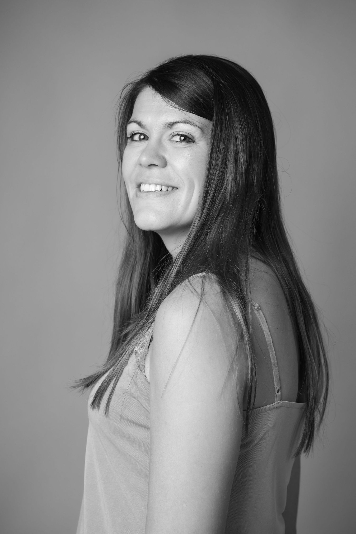 Black and white portrait of a smiling brunette woman with long hair in a sleeveless top.