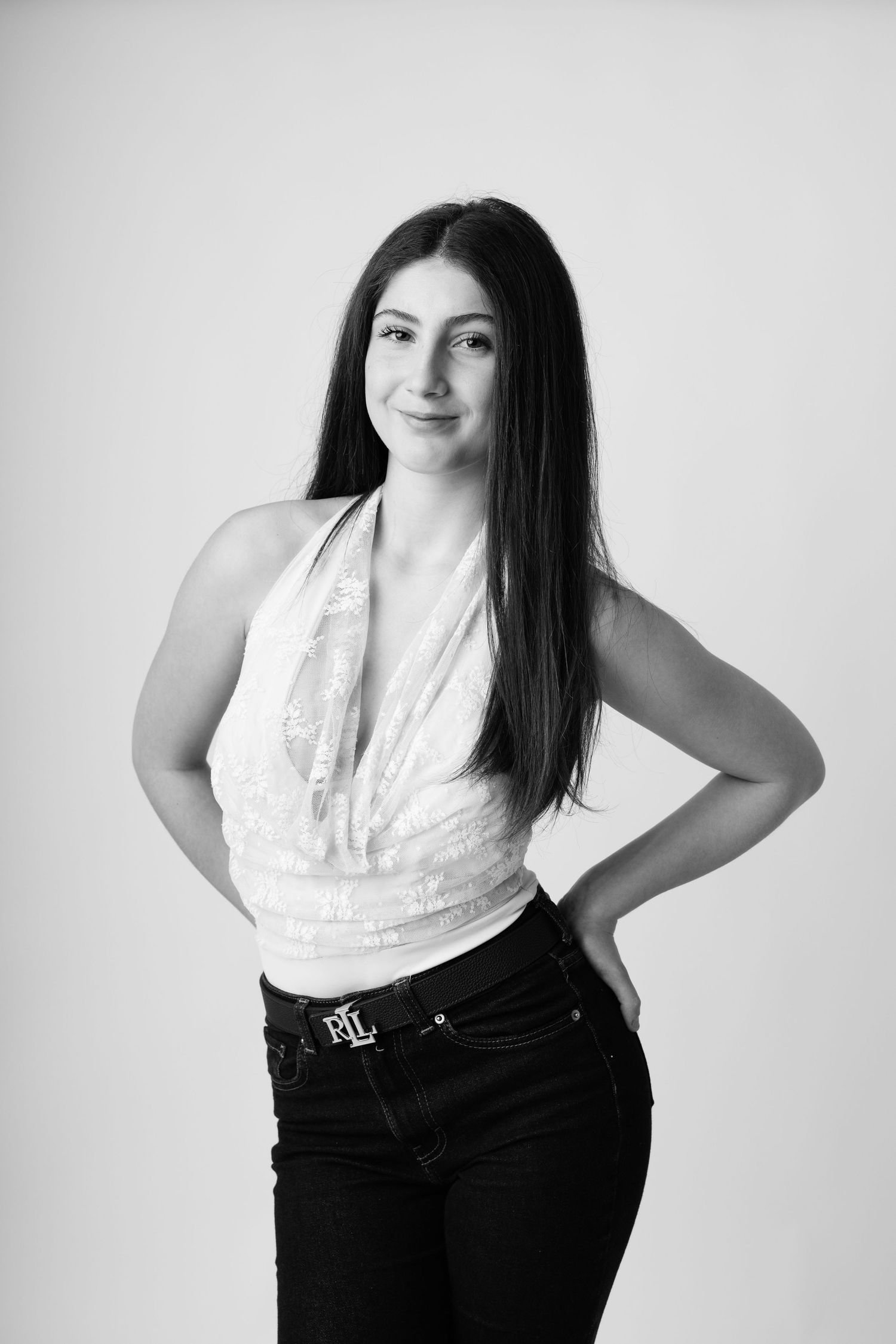 Black and white portrait of a young woman with long dark hair wearing a halter top and Ralph Lauren jeans.