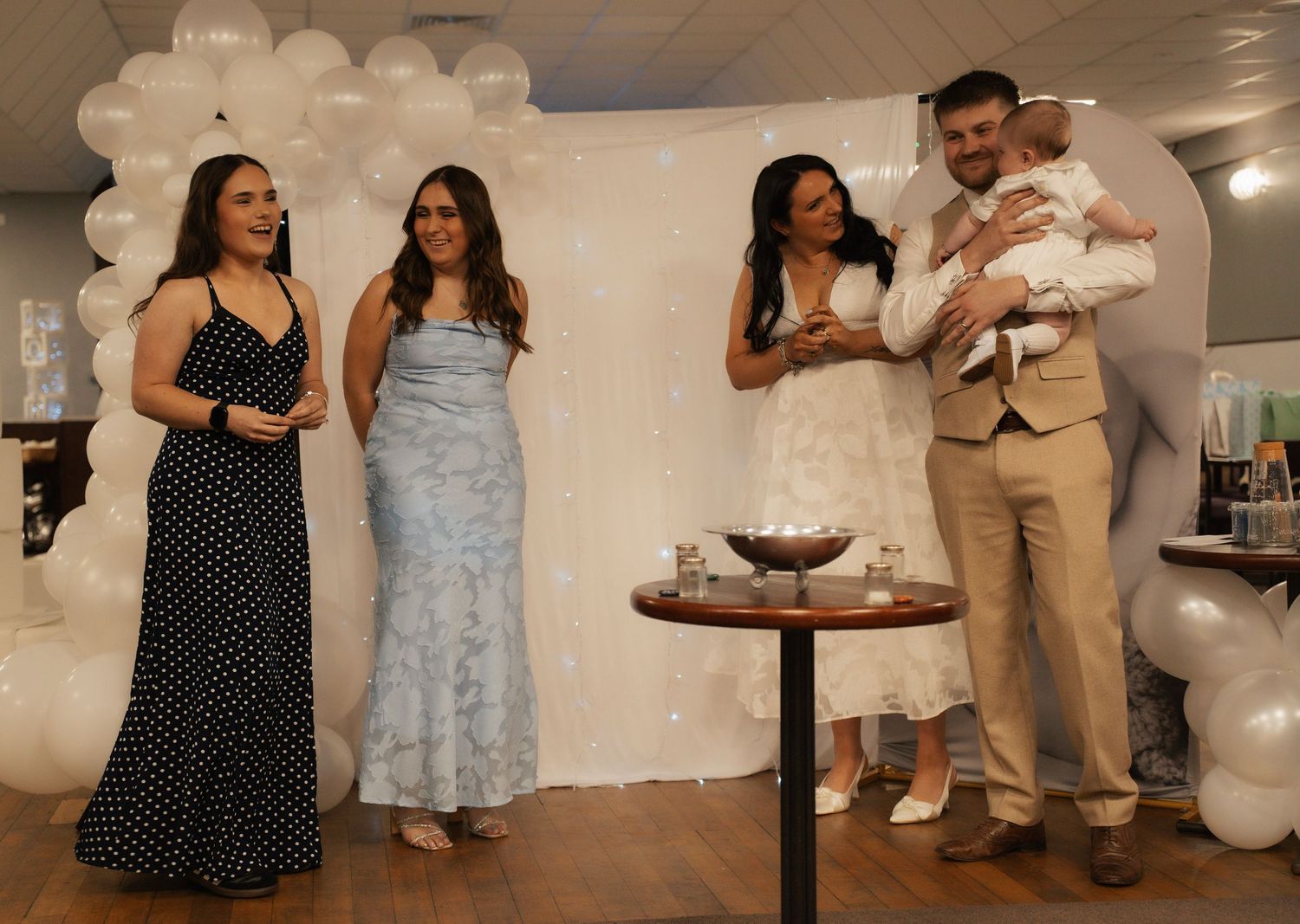 Celebrant lights a small flame in his hand during a white-themed indoor ceremony.