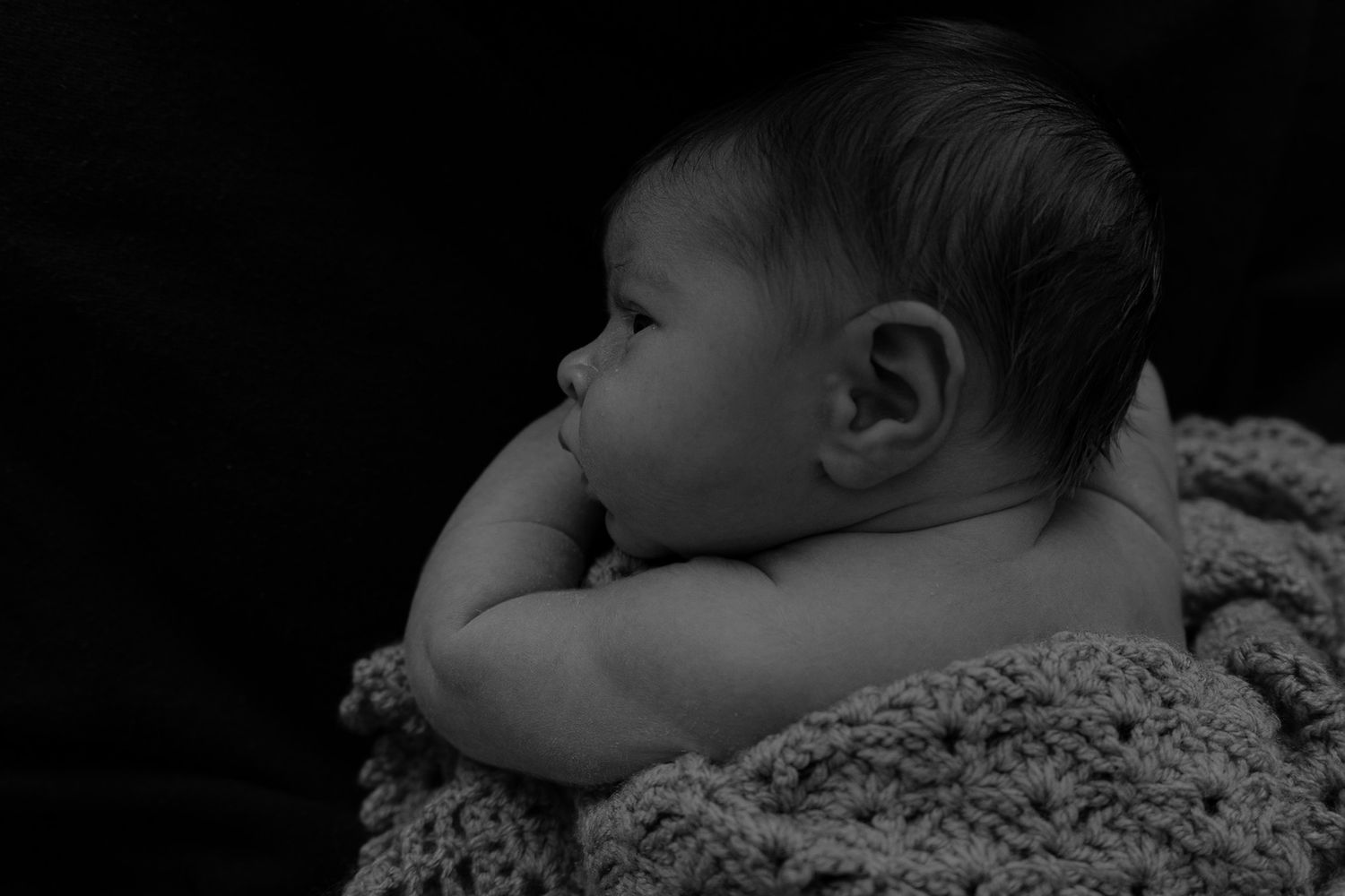 babies profile from behind photographed on a black background.