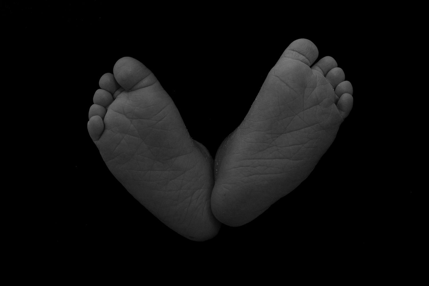 baby feet against a black background.