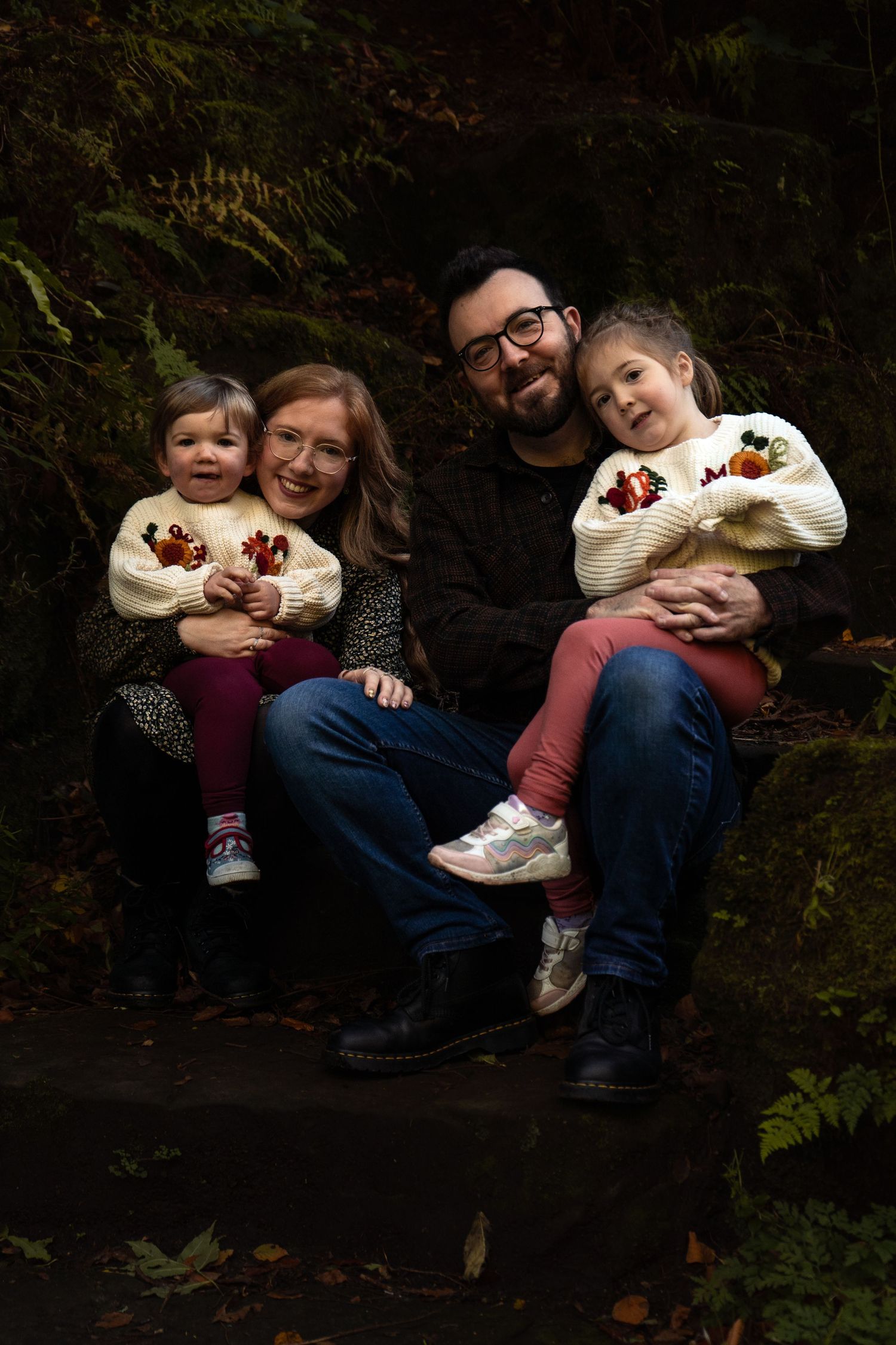 Family photograph with two girls sitting on their parent's knees at Pittencrief Park in Dunfermline.