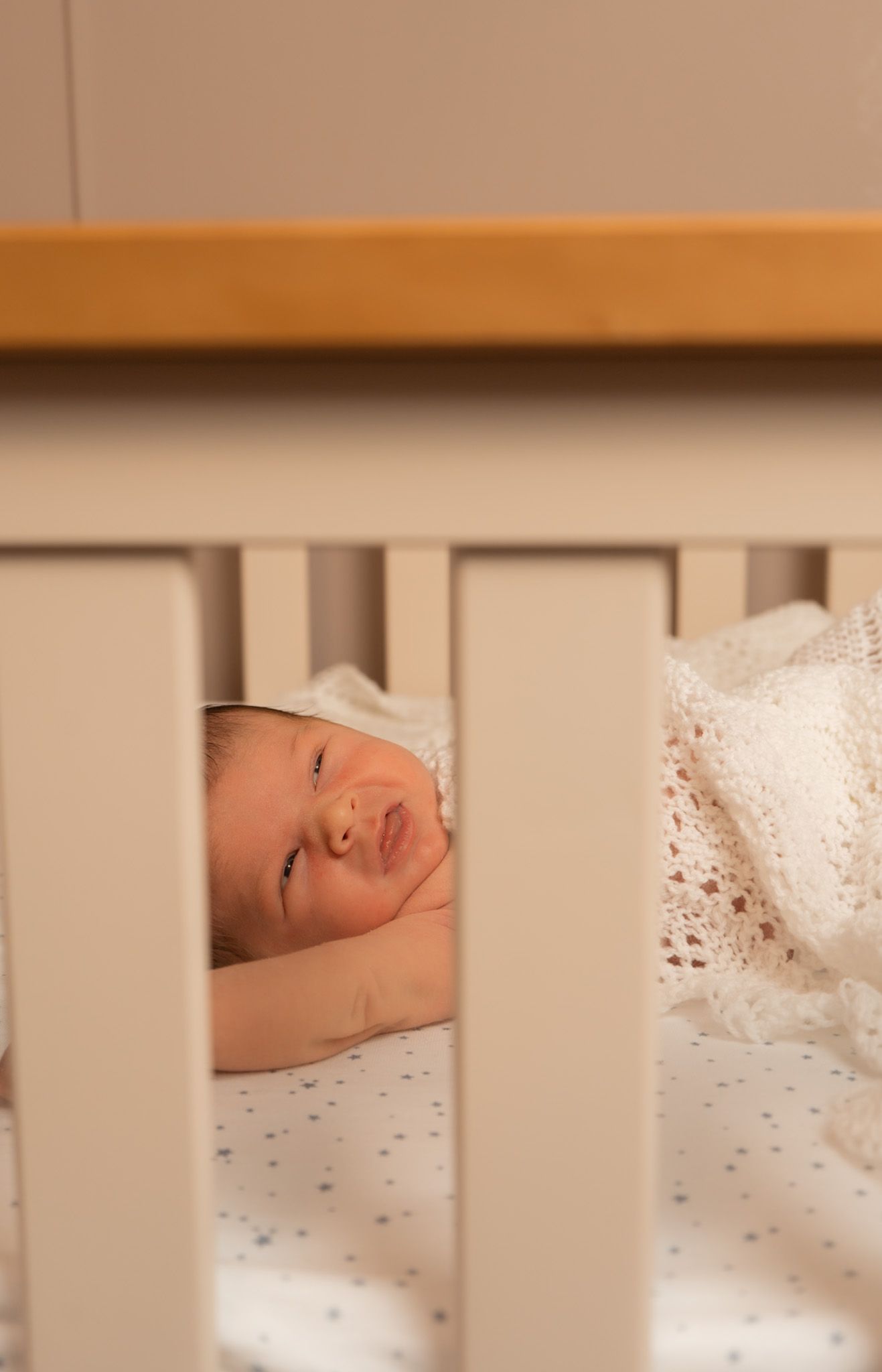 Lifestyle photograph of newborn baby in big cot.