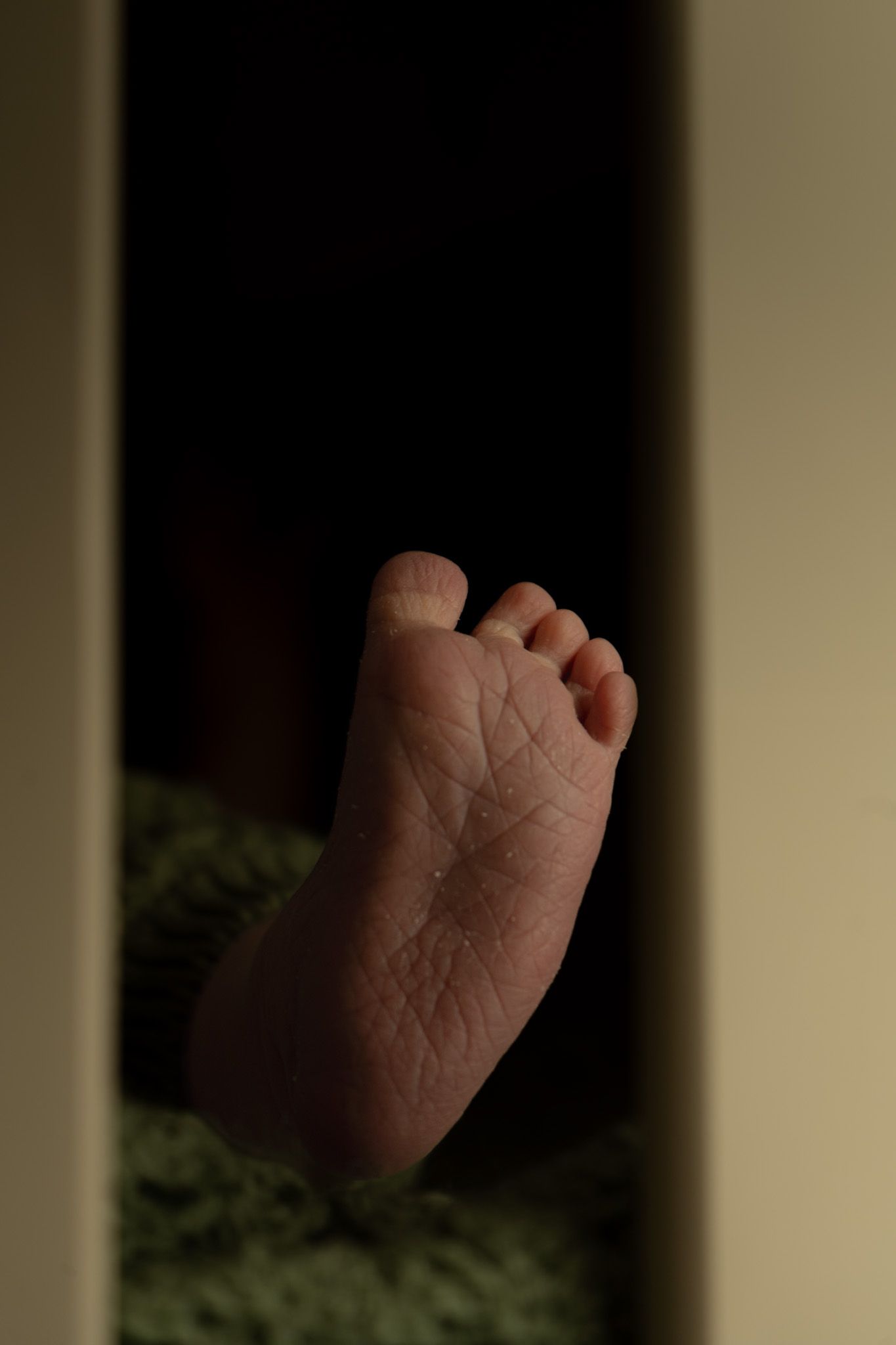 detail shot of baby foot through slats in their cot.