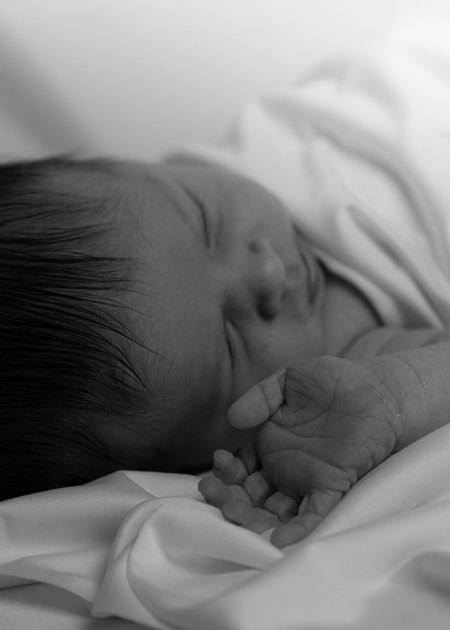 Close up of sleeping newborn baby hand and face.