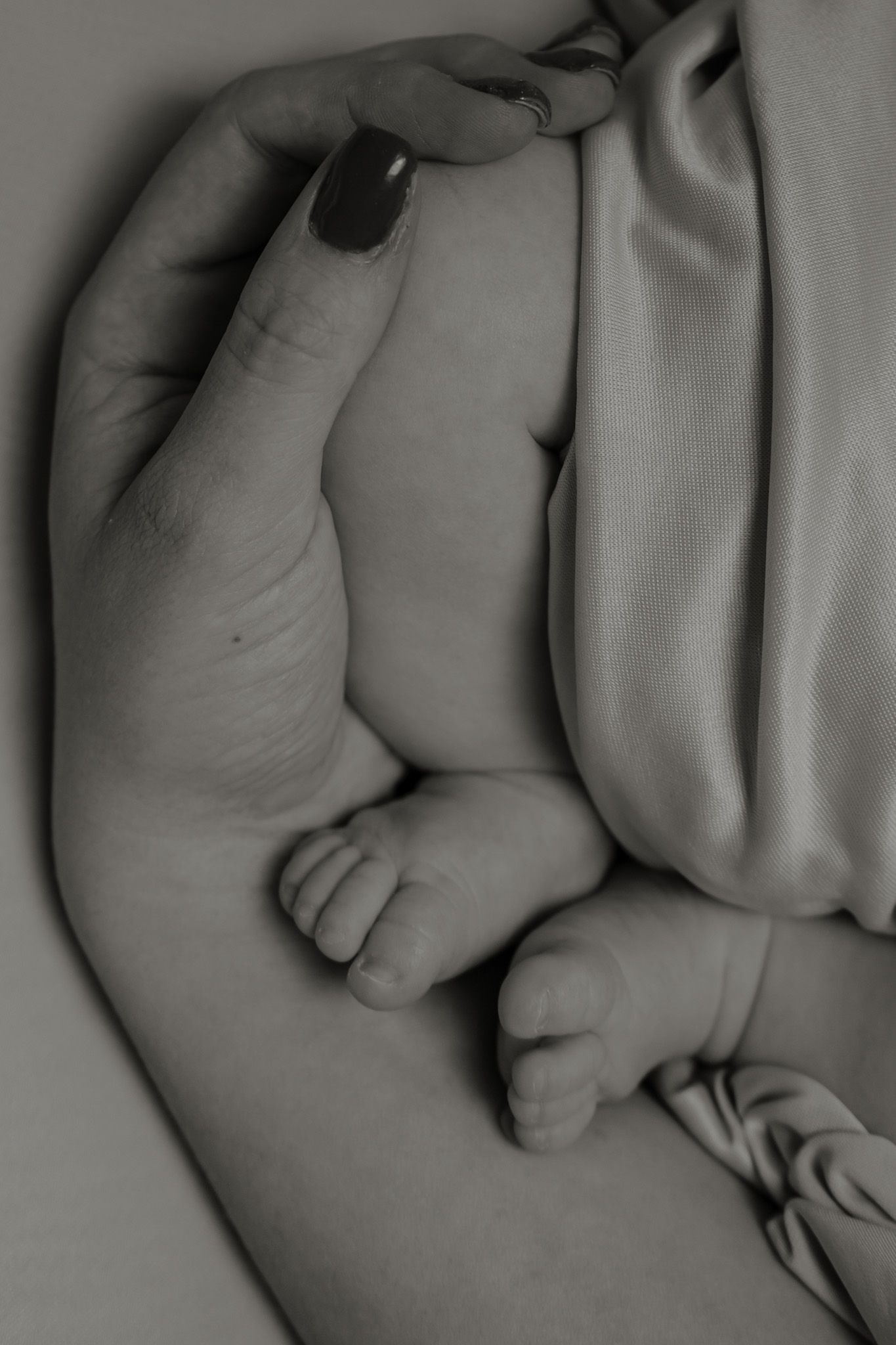 detail photograph of newborn baby feet resting on mum's arm