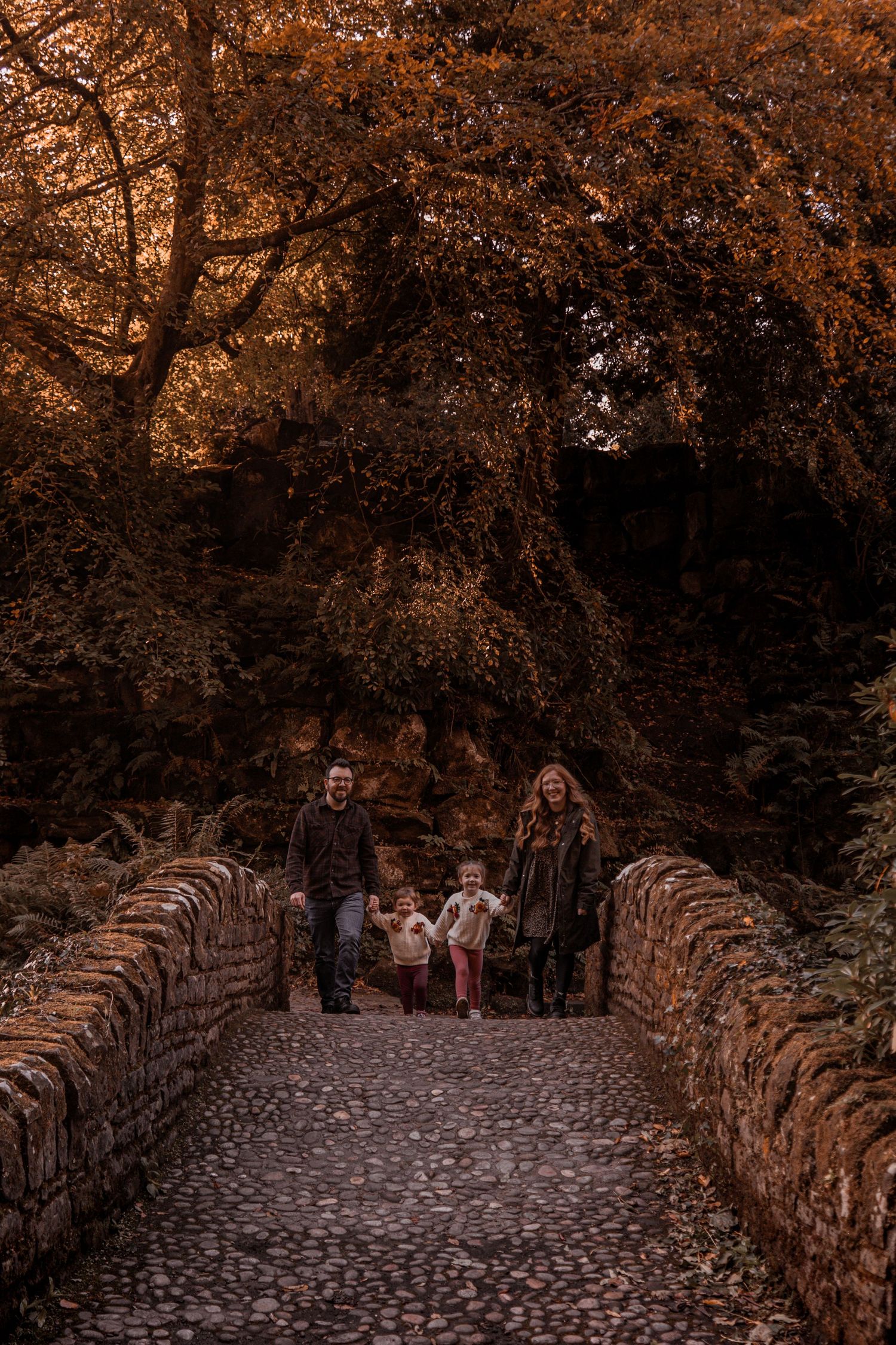 Family photo skipping across the bridge at Pittencrief Park in Dunfermline.