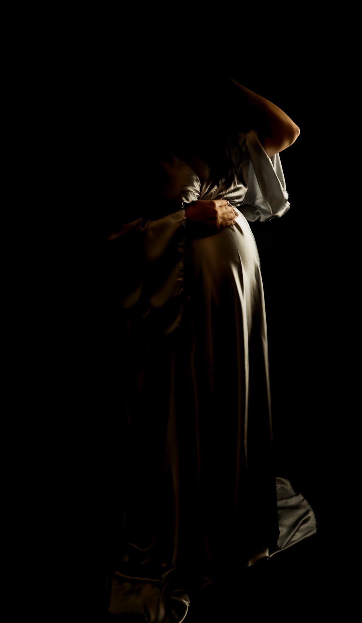 studio maternity photo, mum-to-be photographed in a gold dress with hand resting on bump.