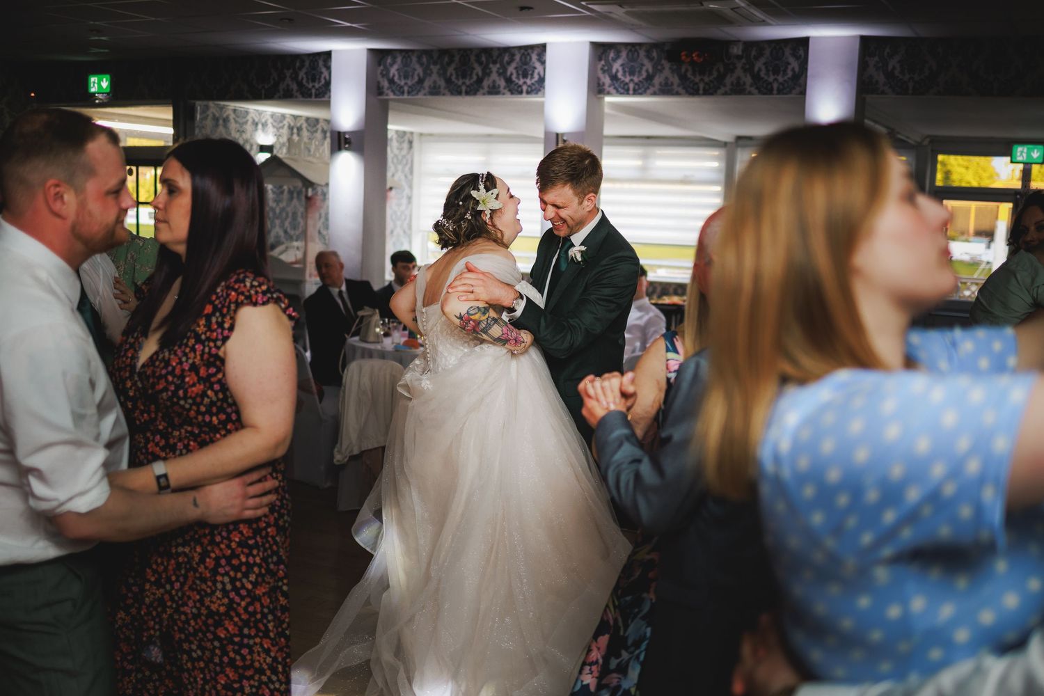 Bride and groom share first dance surrounded by guests at elegant wedding reception venue.