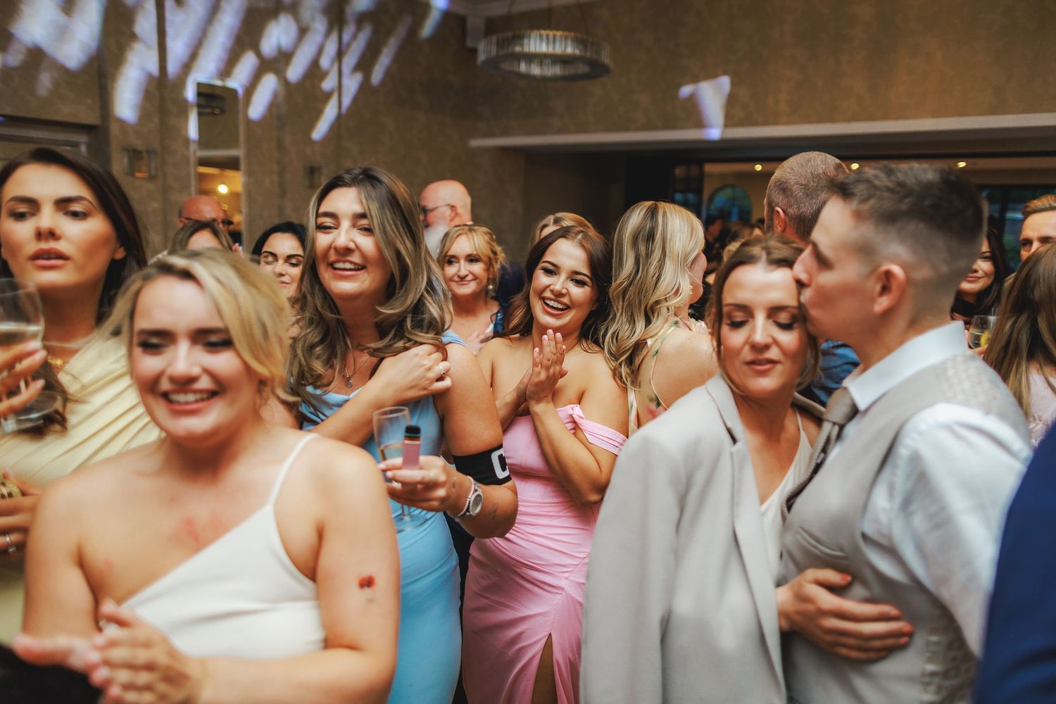 Guests dancing and celebrating at a lively wedding reception party indoors.
