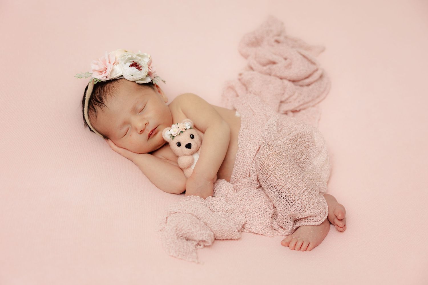 Delicate newborn photo session with soft pink tones and lace details.