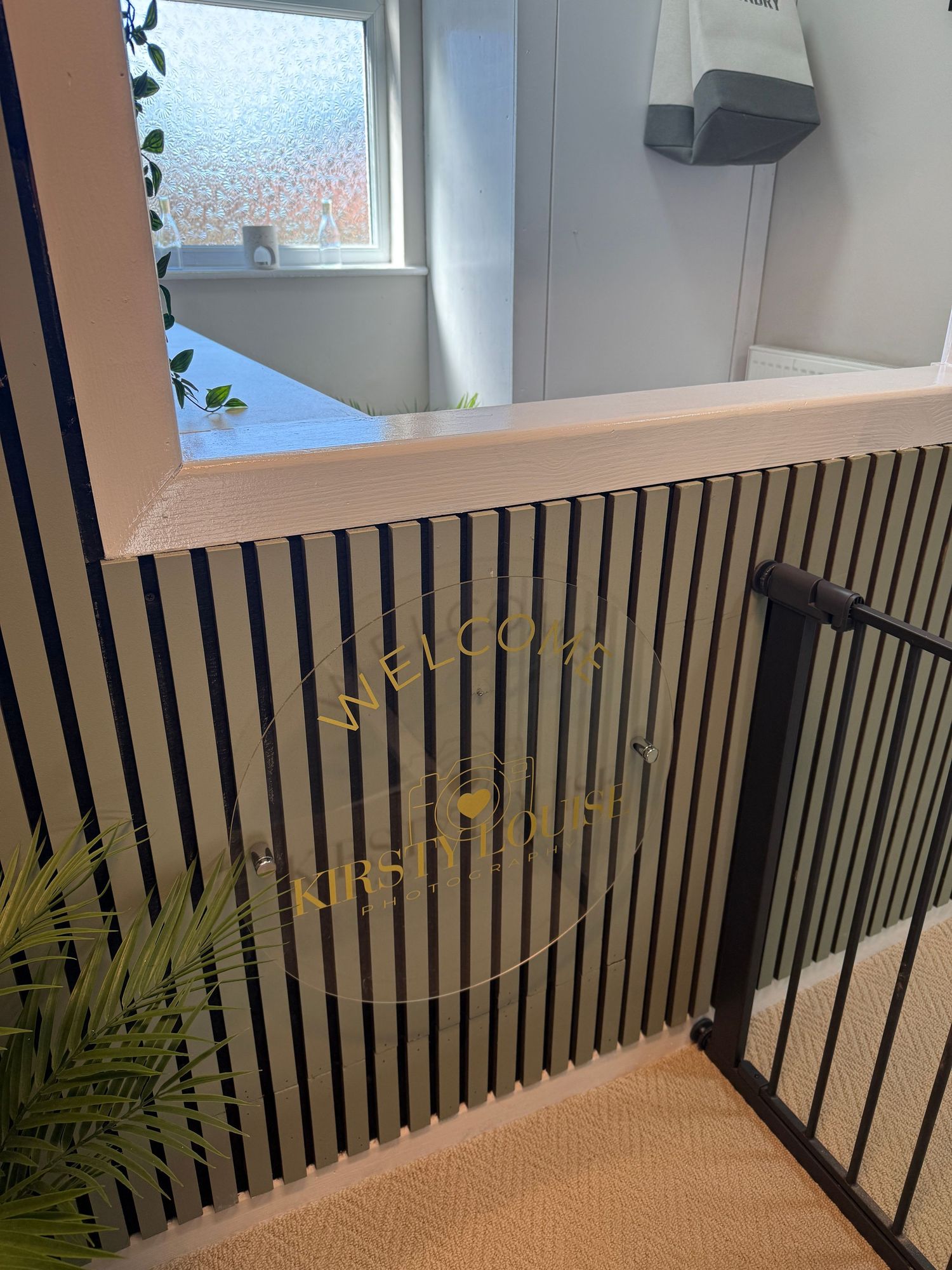 Welcome sign on striped black and white wall panel at top of staircase with safety gate.