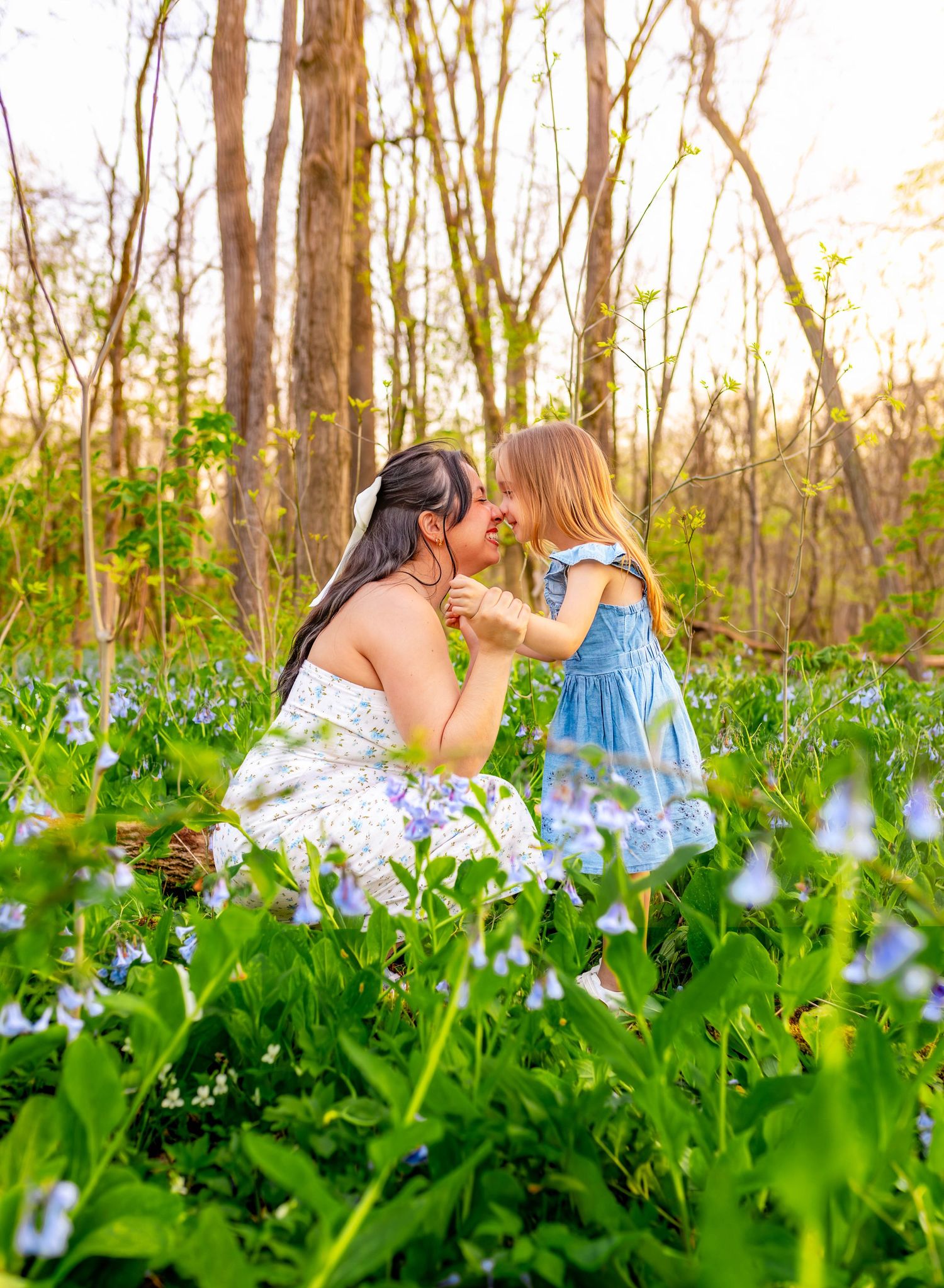 Mom and Daughter photoshoot among blooming blue wildflowers in a wooded setting.