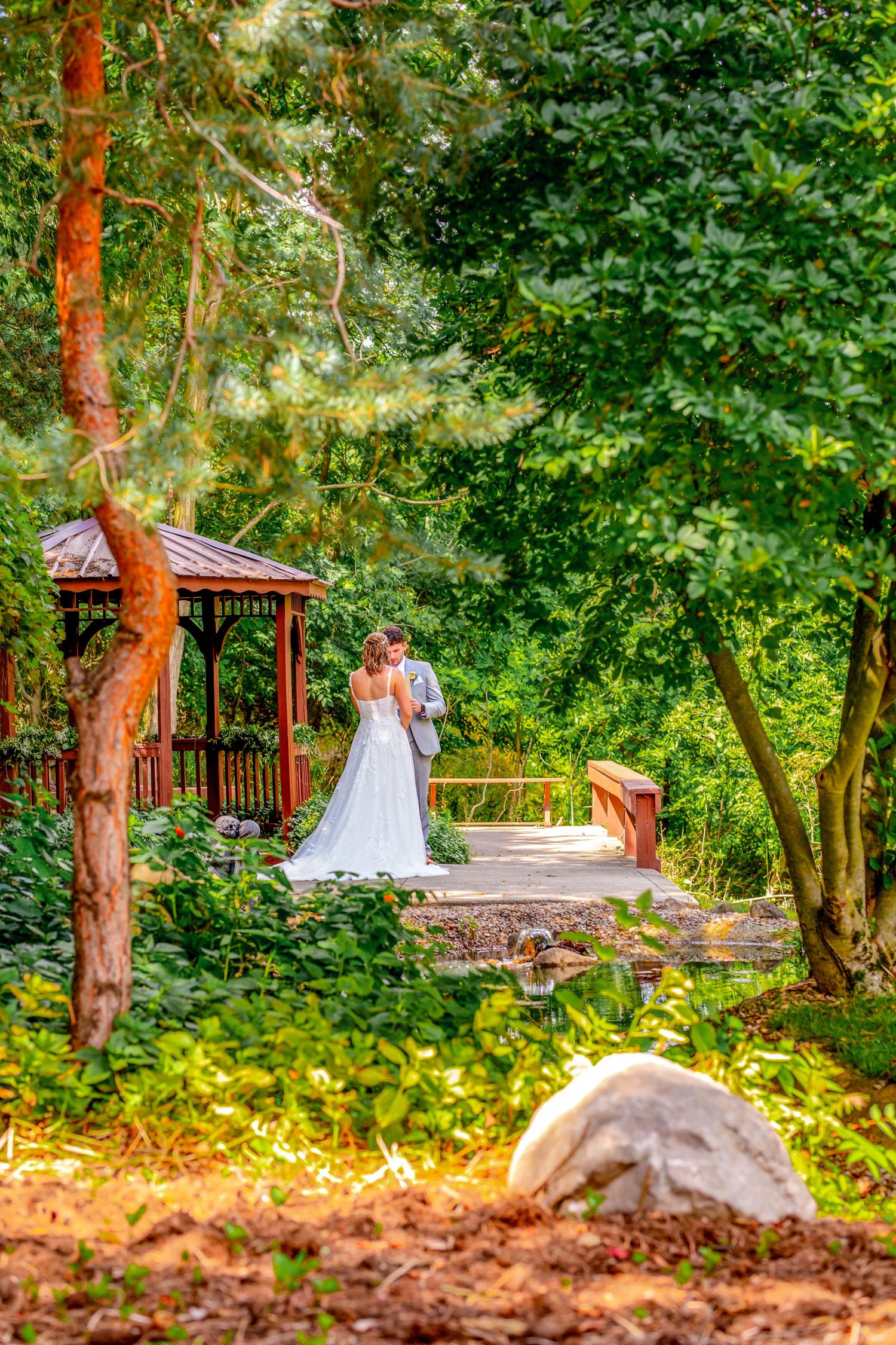 Scenic garden walkway with wooden gazebo surrounded by lush greenery.