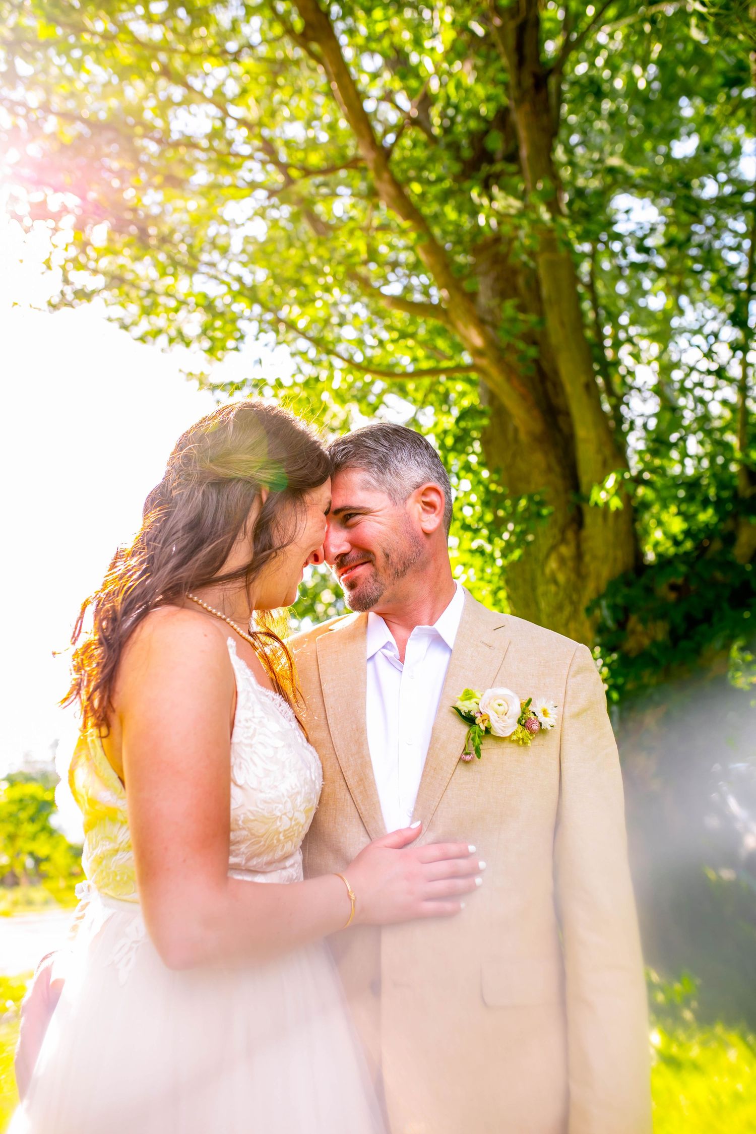 Romantic wedding moment captured in a sun-drenched garden with golden light filtering through trees.