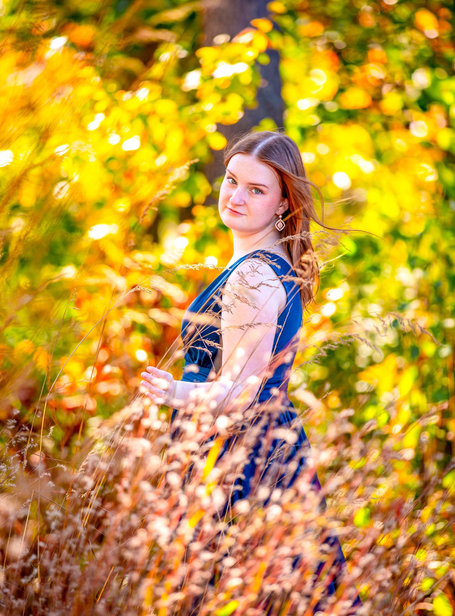 Fall portrait session in golden natural lighting with autumn foliage backdrop.