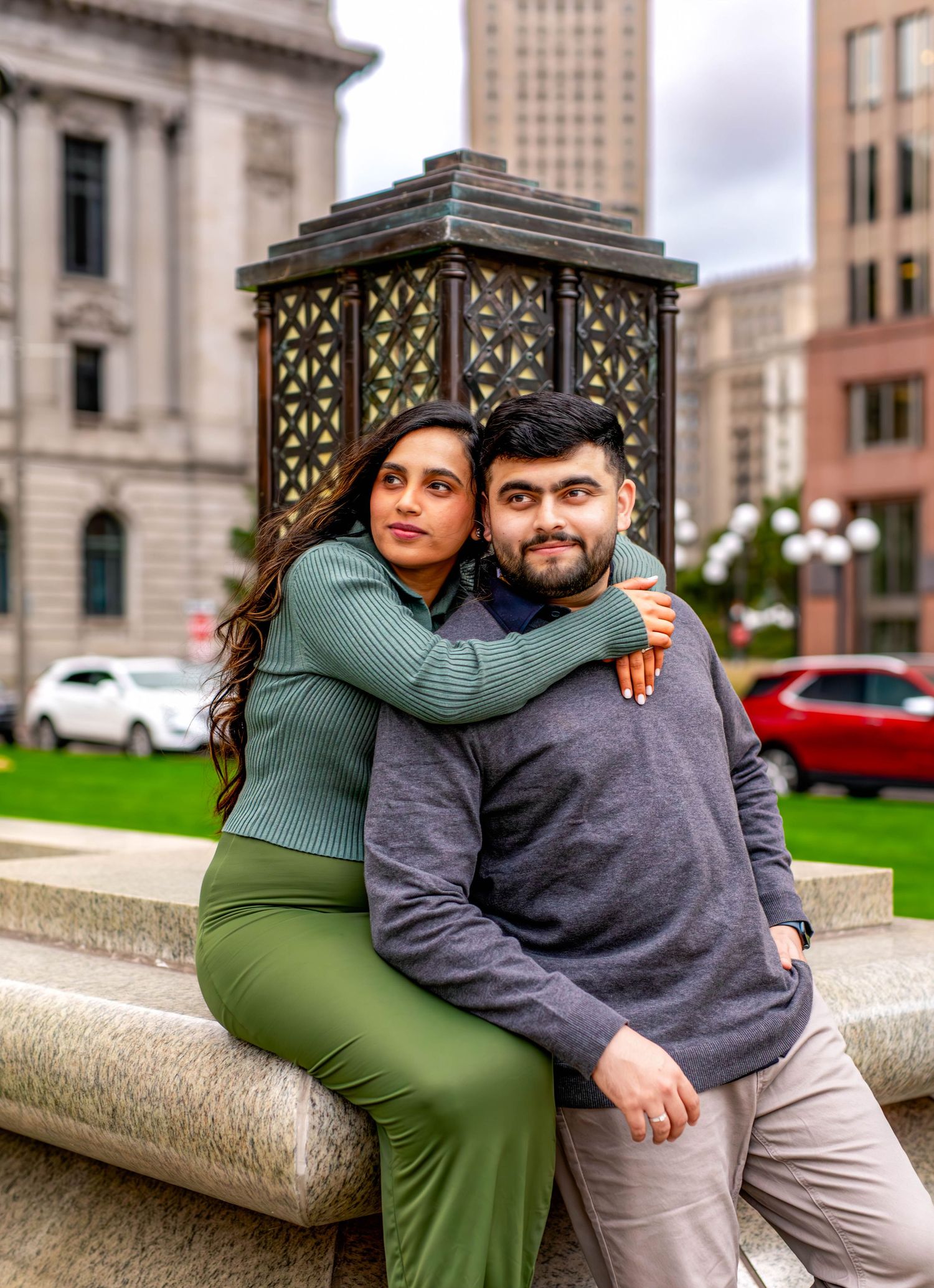 Couple embracing on stone steps outside historic city buildings.