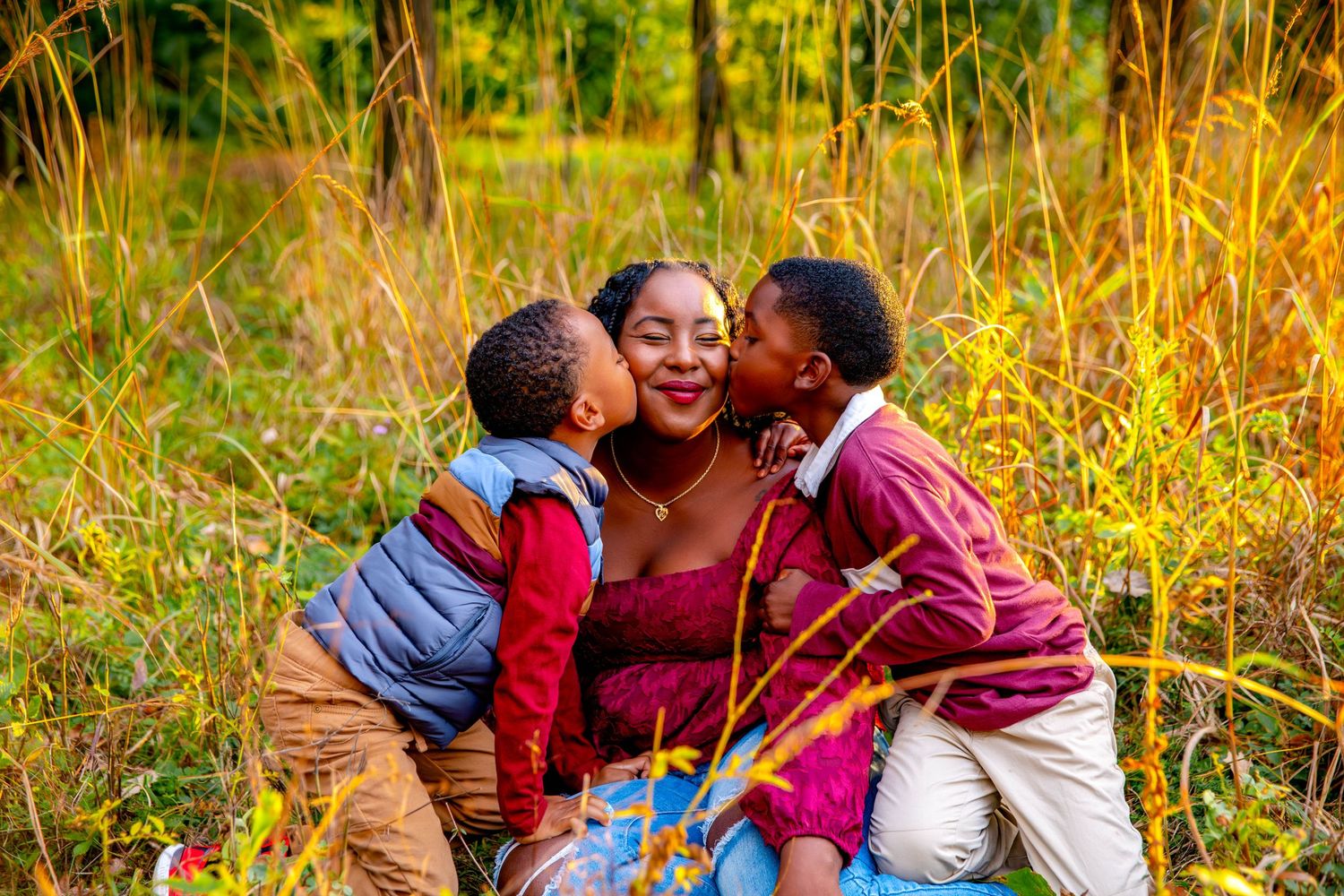 Family enjoying a warm sunset together in tall golden grass during an outdoor photo session.