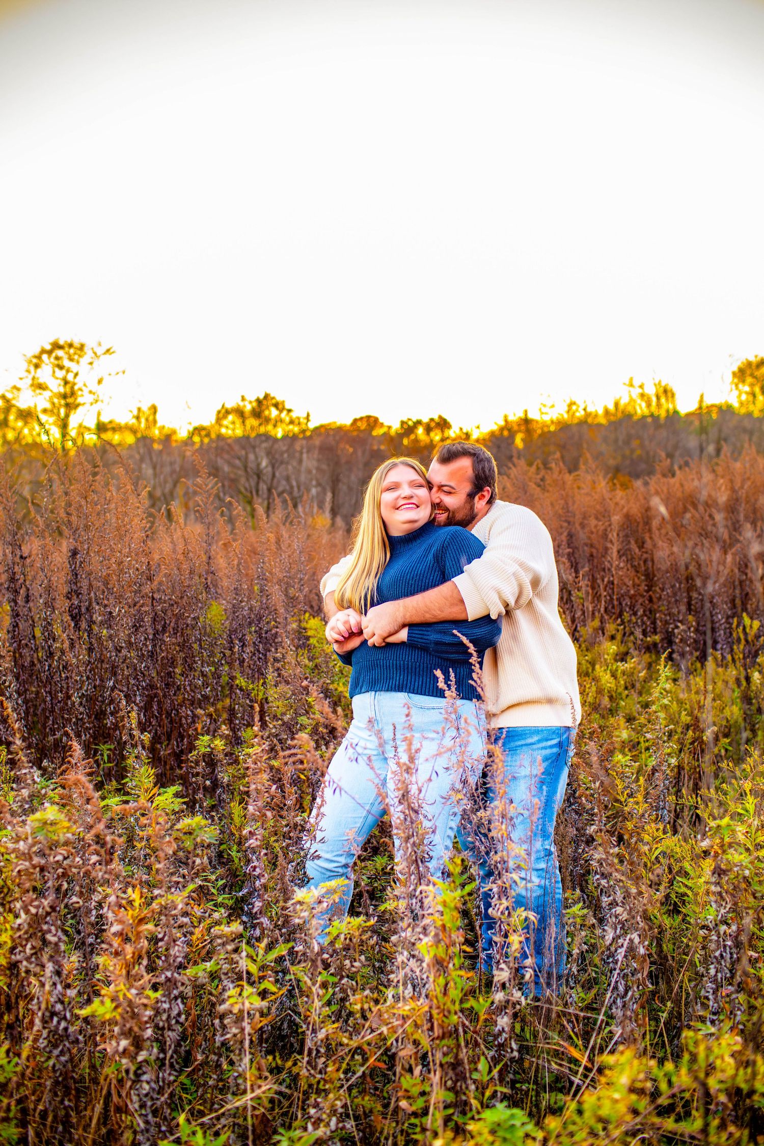 Casual couple embracing in wildflower field during golden hour.