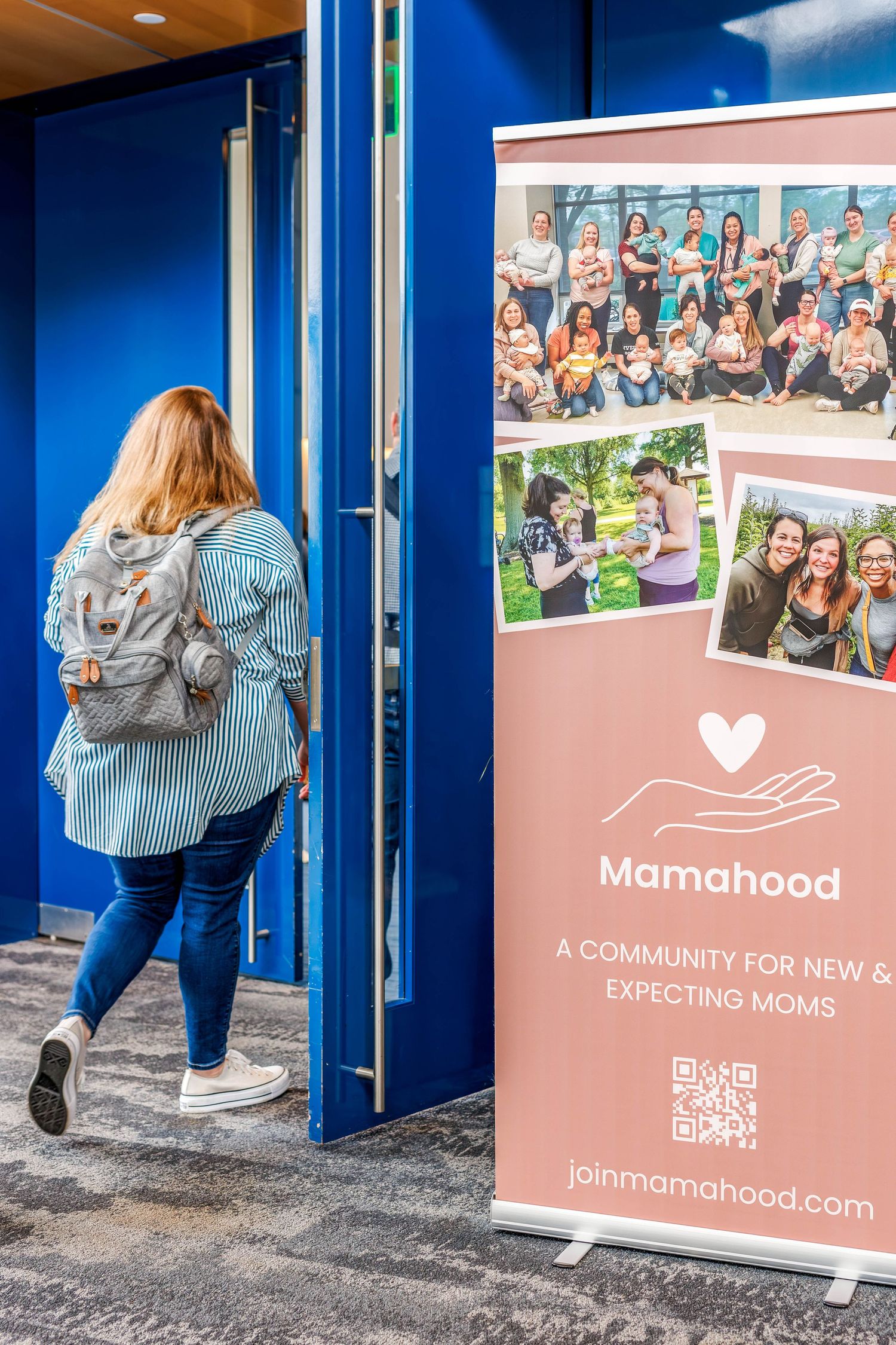 Marketing banners and branding displays for mamahood community organization against blue walls.