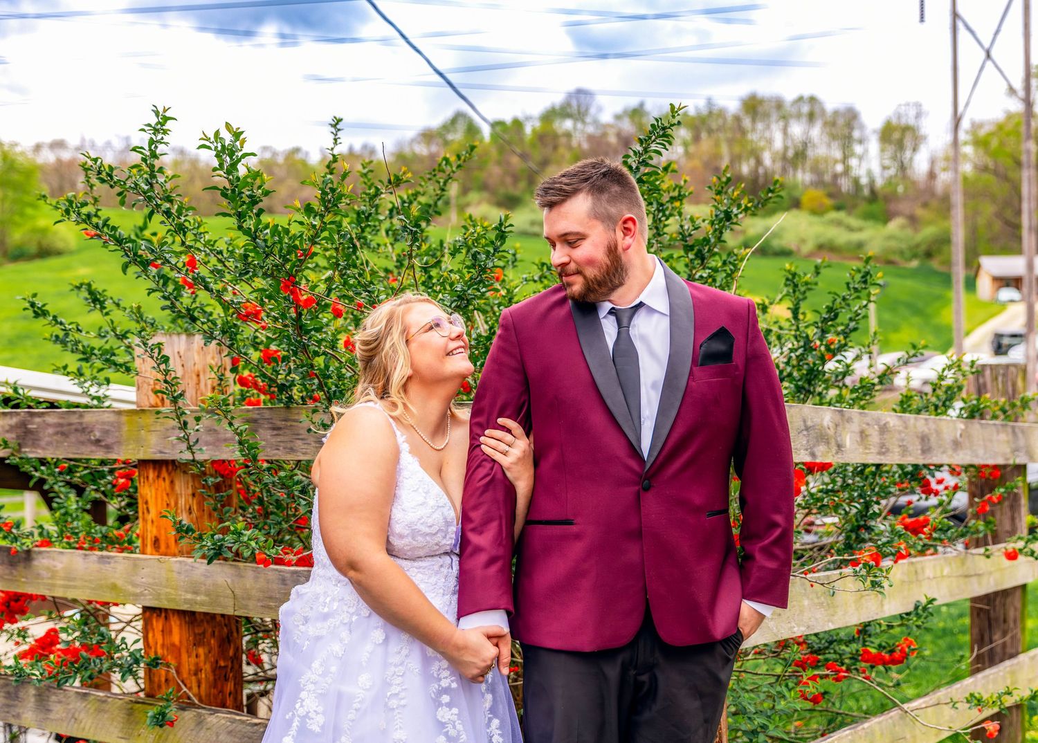 Couple walking along wooden pathway in garden setting wearing formal attire.