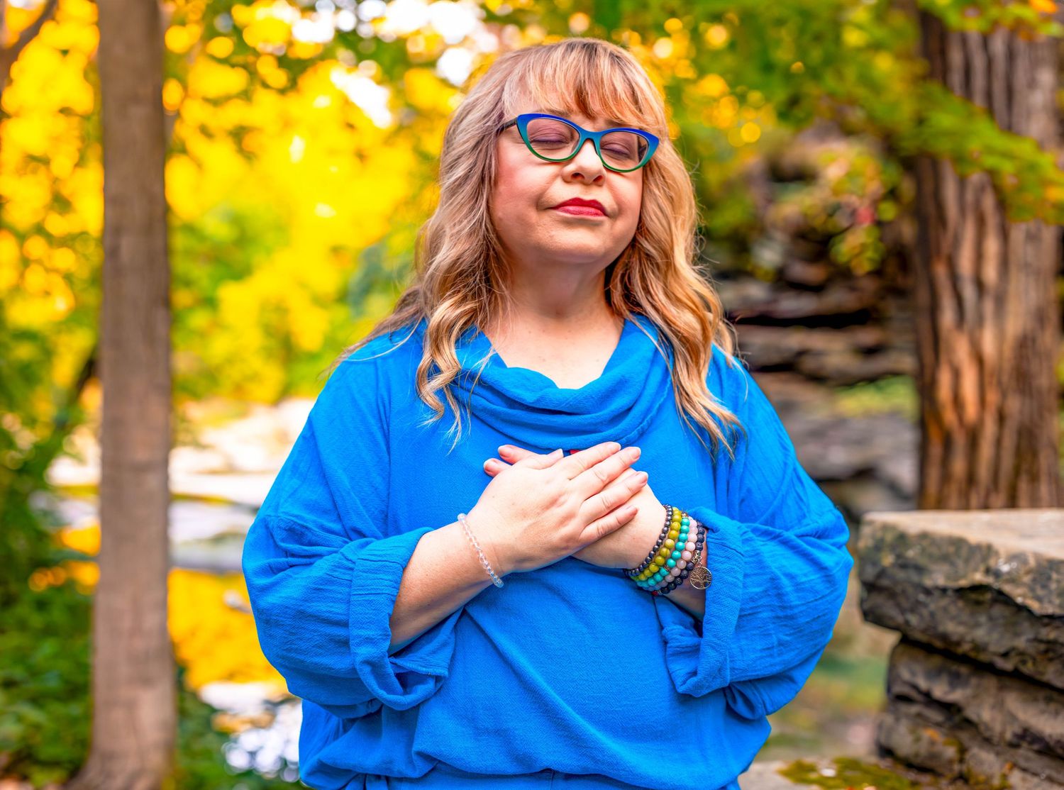 Blue sweater and colorful bracelets against a warm autumnal background.