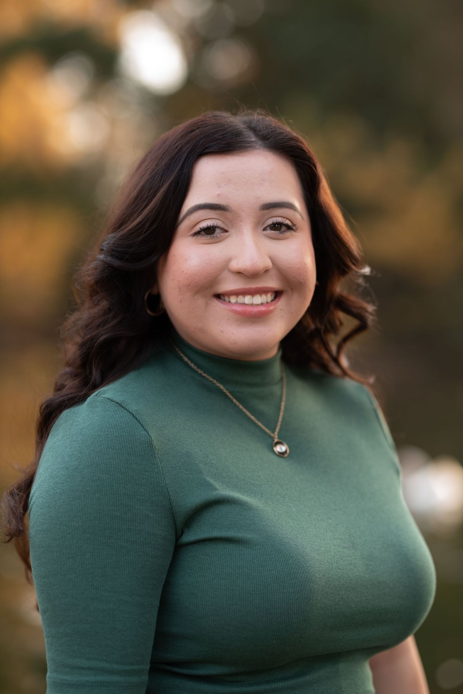 Portrait sequence in green turtleneck against blurred natural backdrop.