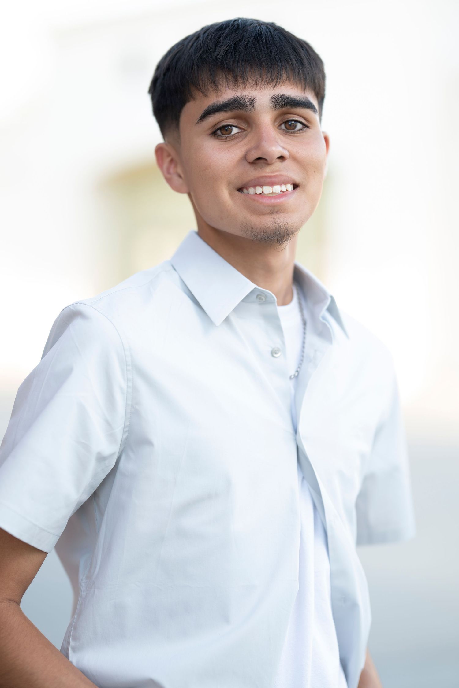 Portrait series of a person in white button-down shirt against bright white background.