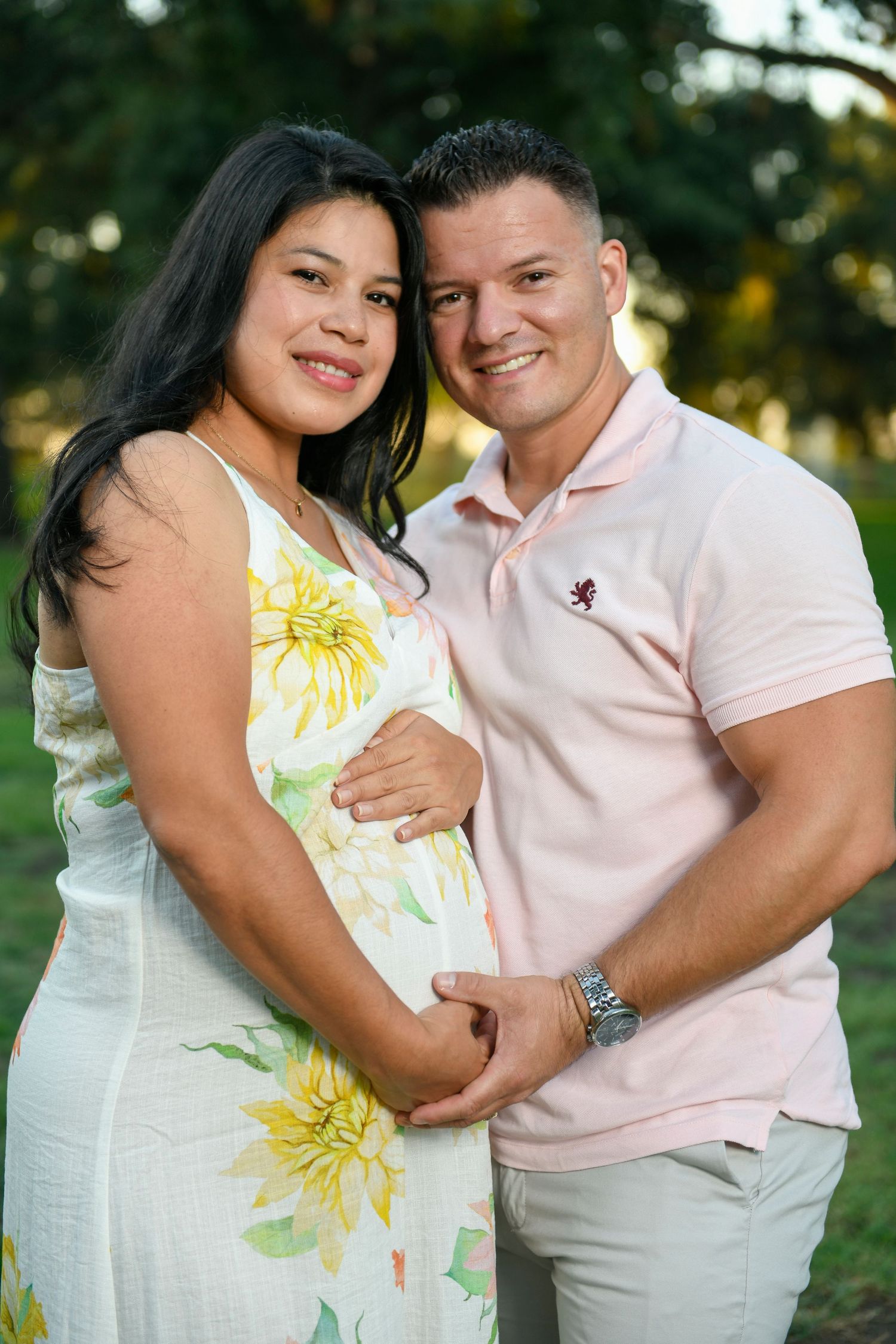 Couple in light colored outfits embracing during an outdoor photo session with floral dress details.