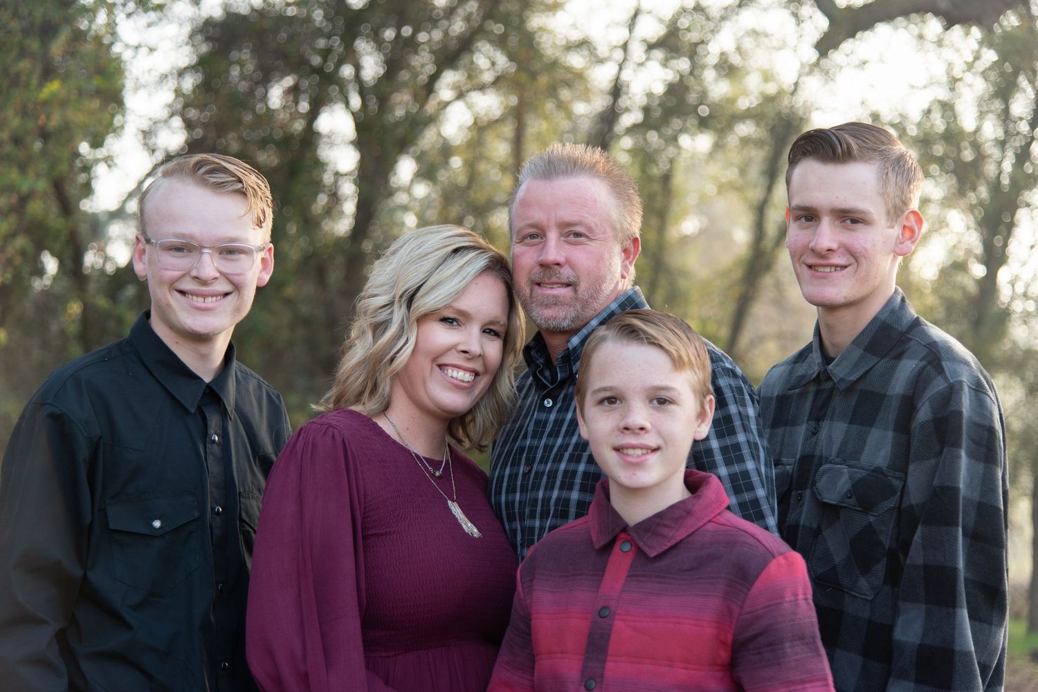 Family portrait session captured in outdoor setting with matching burgundy outfits.