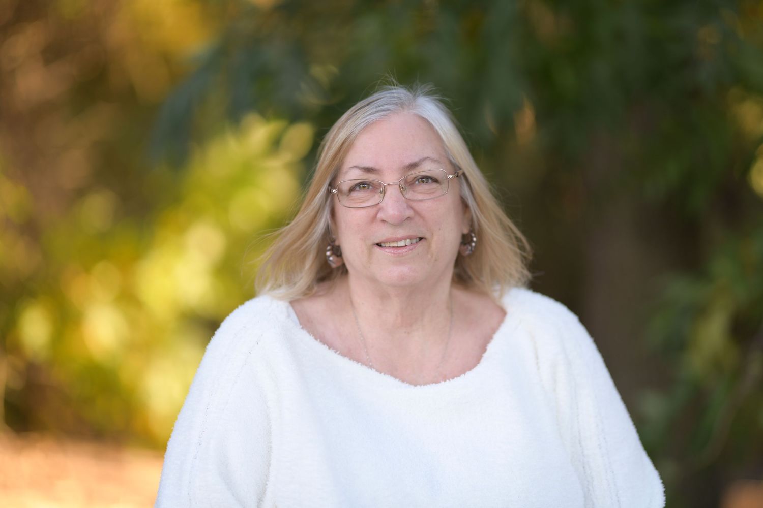 Portrait series of a person in white clothing outdoors with natural lighting and foliage.
