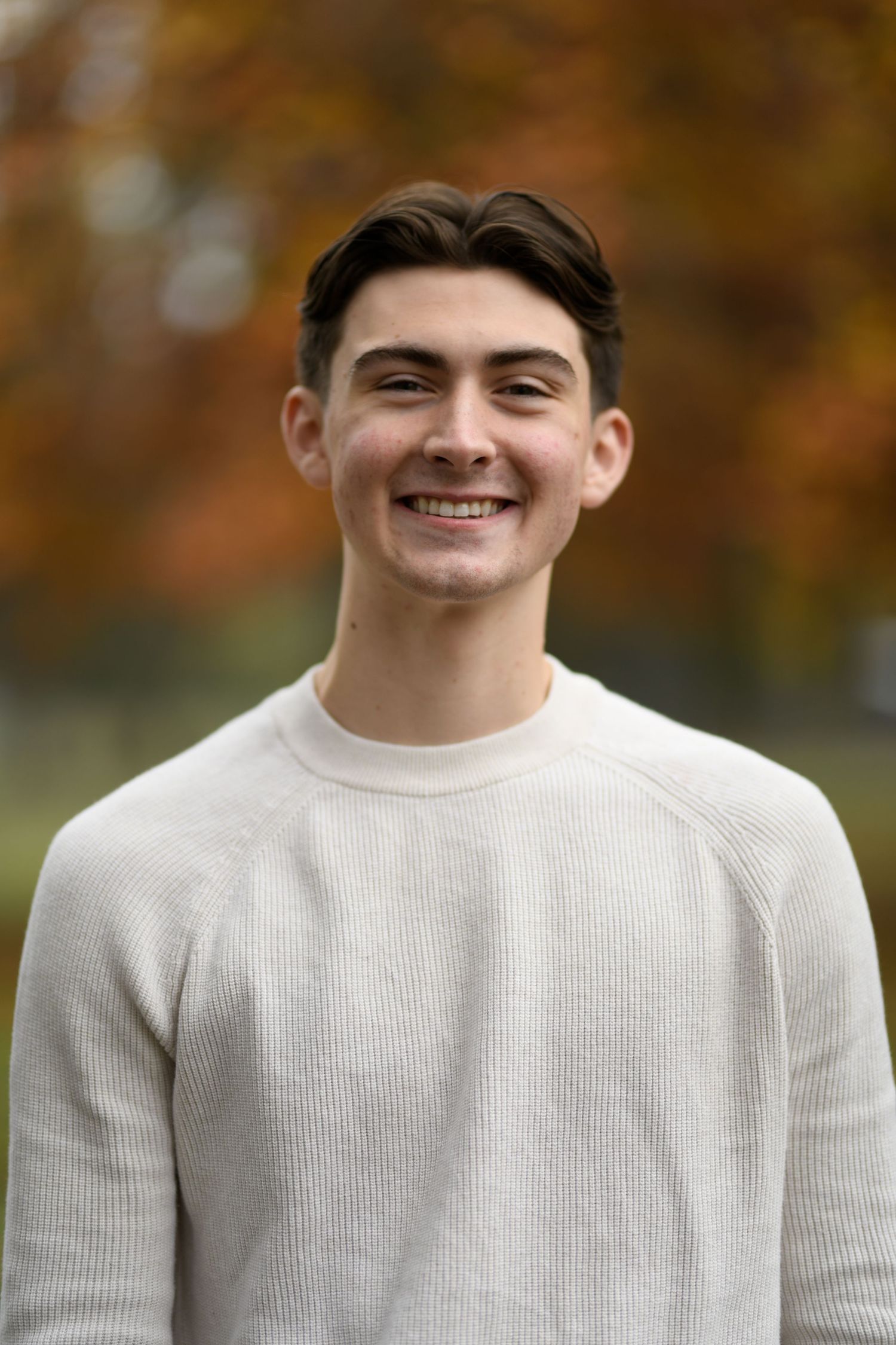 Person in white sweater shown in progressive smiling shots against autumn background.