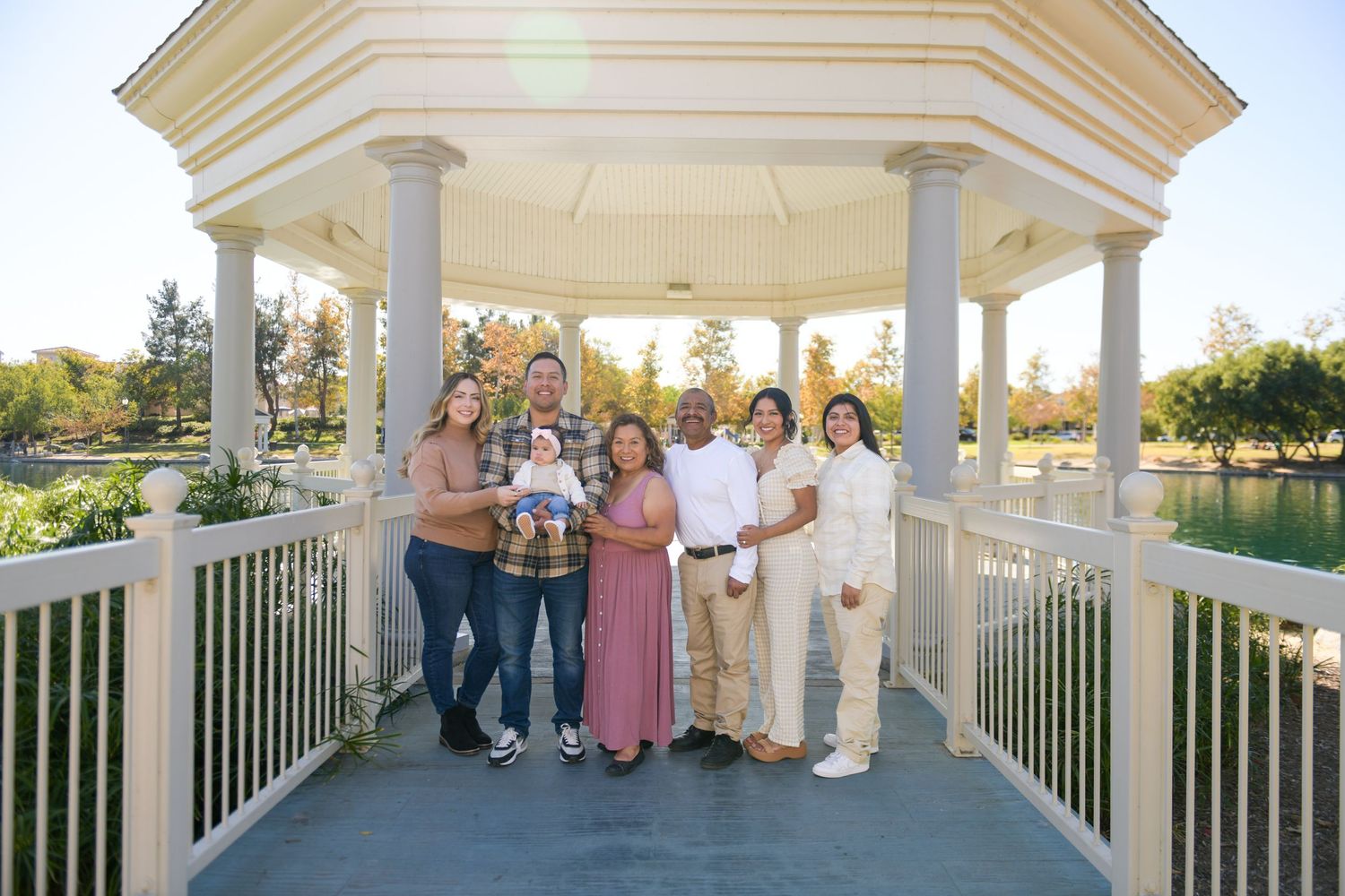 A group stands together in formal attire on a white gazebo deck during sunset.