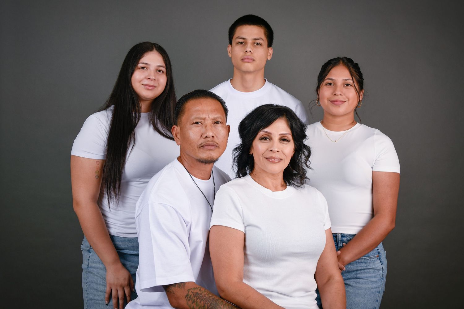 A series of family portraits showing people wearing matching white t-shirts against a dark gray background.