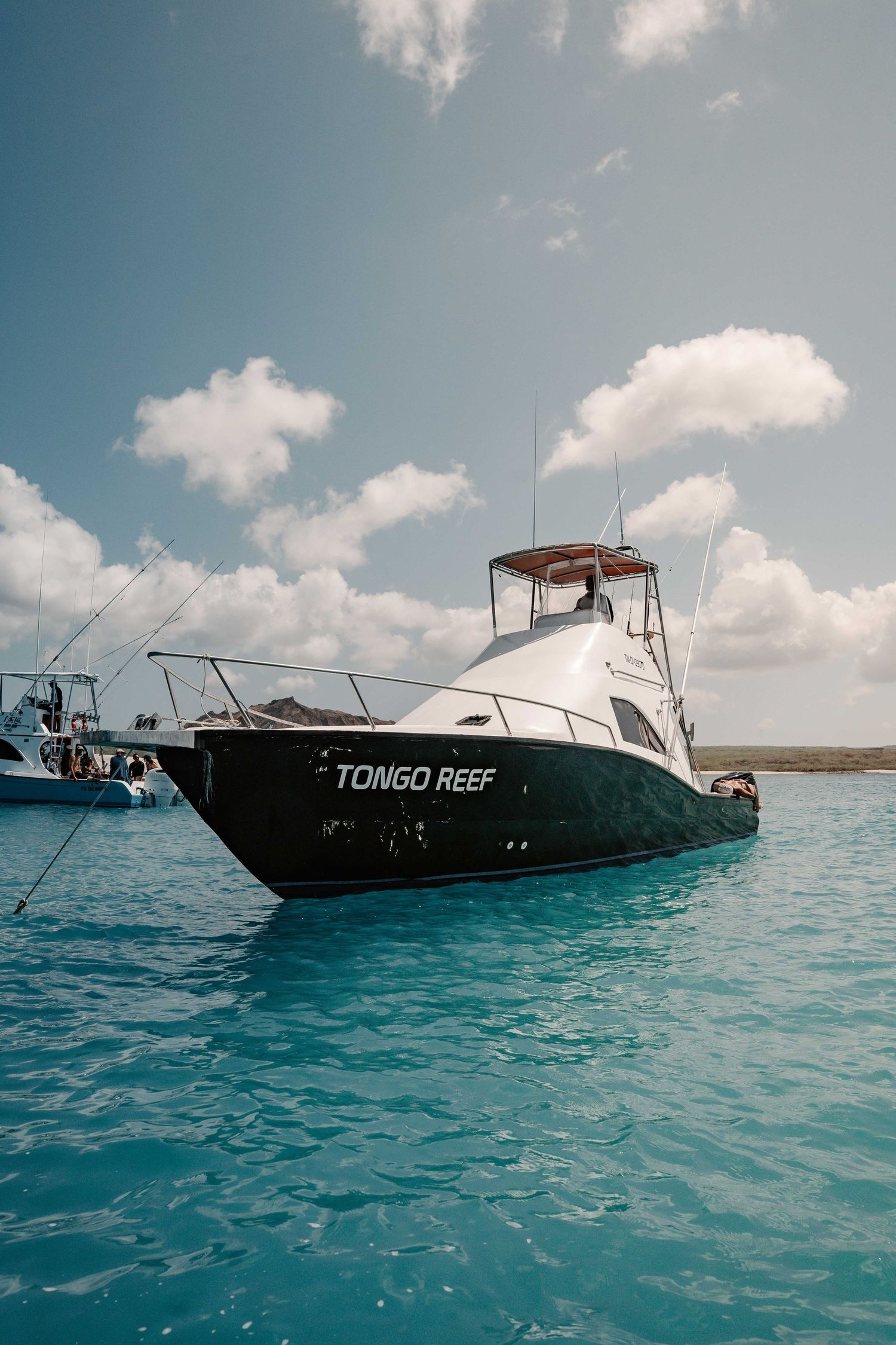 Luxury yacht named Tongo Reef anchored in crystal clear turquoise waters.