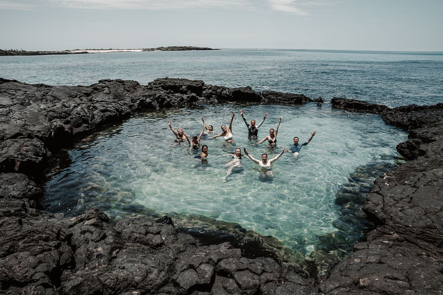 People enjoying the crystal clear waters and rocky coastline of a tropical beach destination.