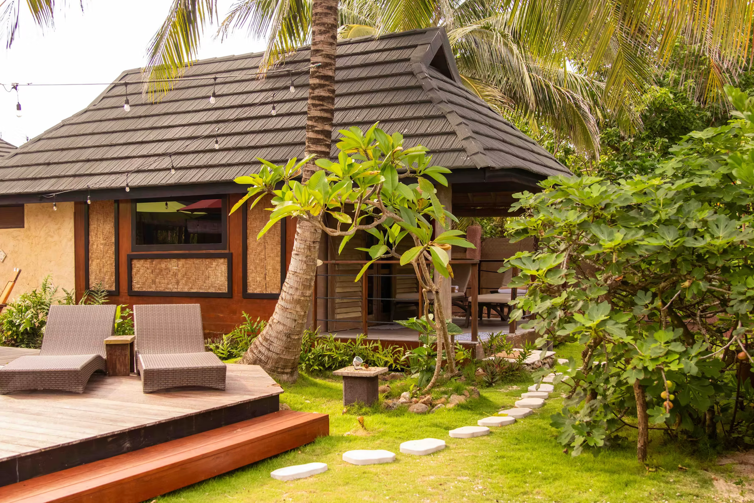 Luxury beachfront villa with thatched roof bungalows and tropical landscaping along a pristine coastline.
