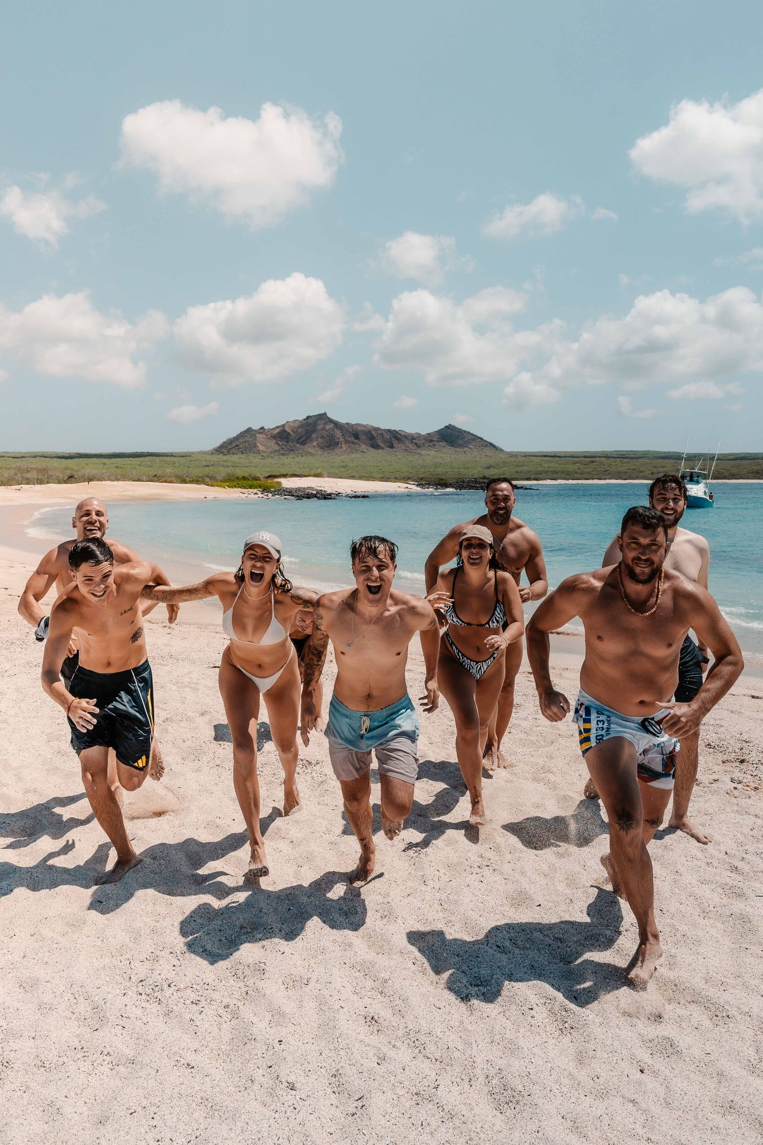 A group enjoying a sunny day together on a white sandy beach with mountains in the background.