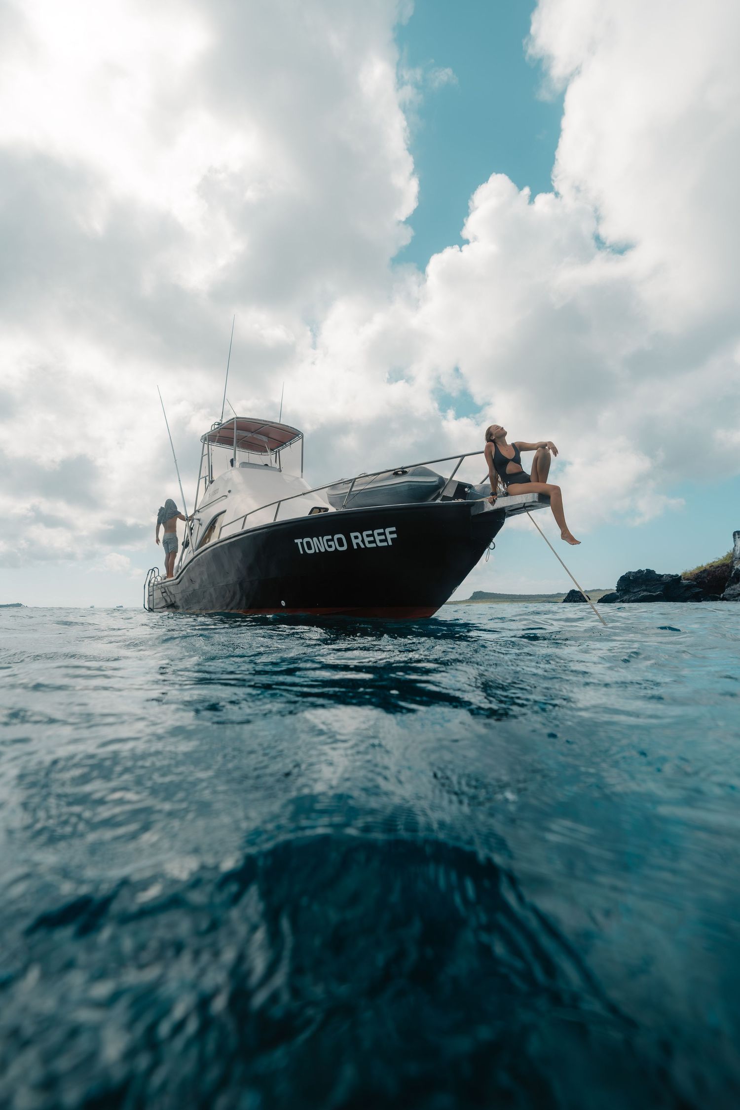 Boat  floating on blue ocean waters with someone diving in.