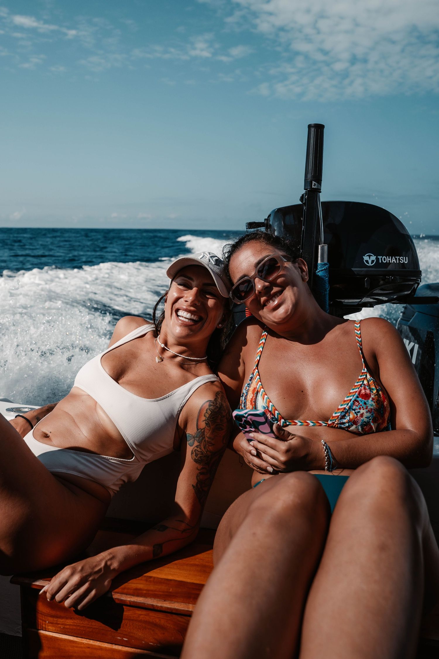 People relaxing and sunbathing on wooden boat deck during ocean cruise.