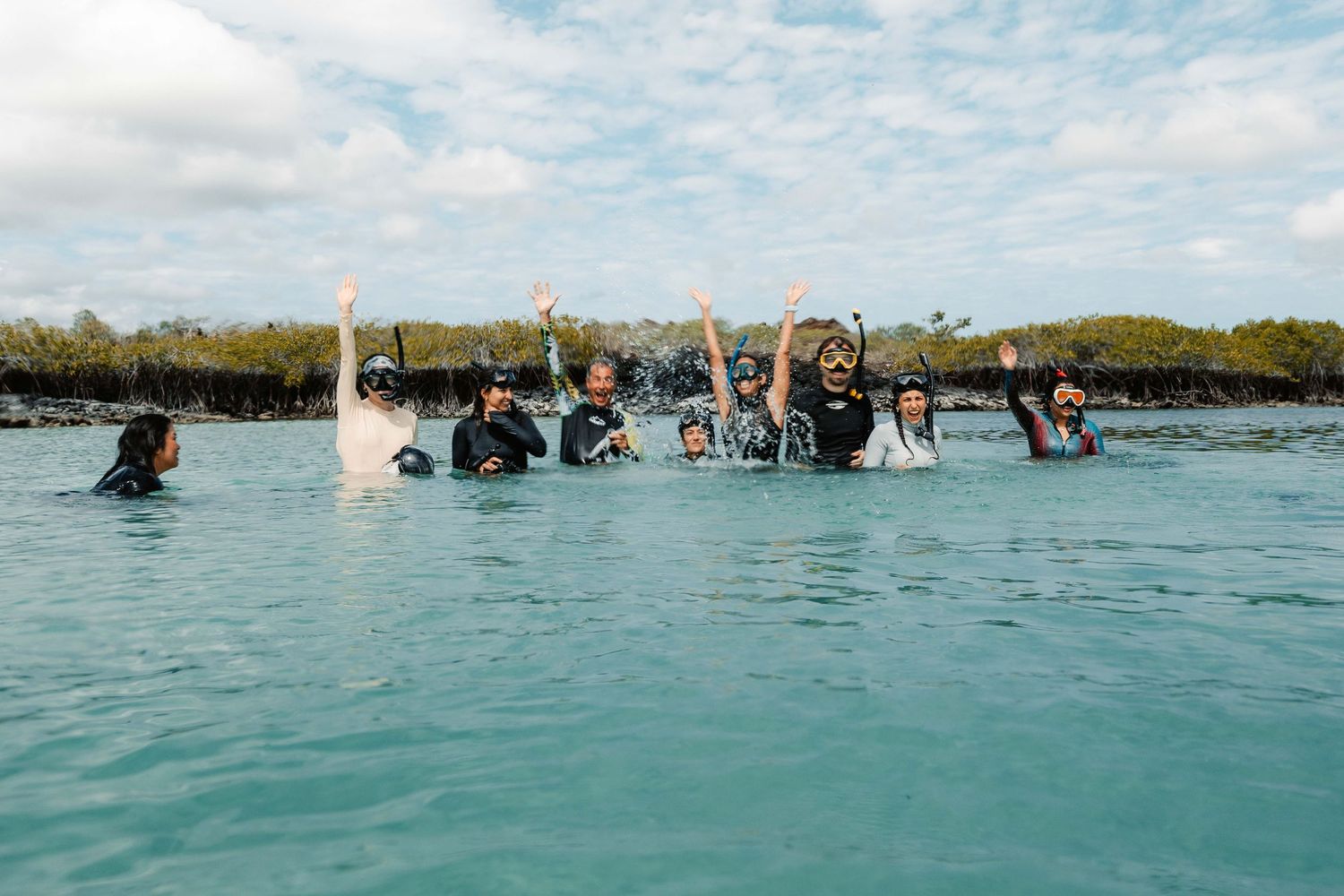 People enjoy water activities and jet skiing in a scenic tropical lagoon on a sunny day with blue skies.