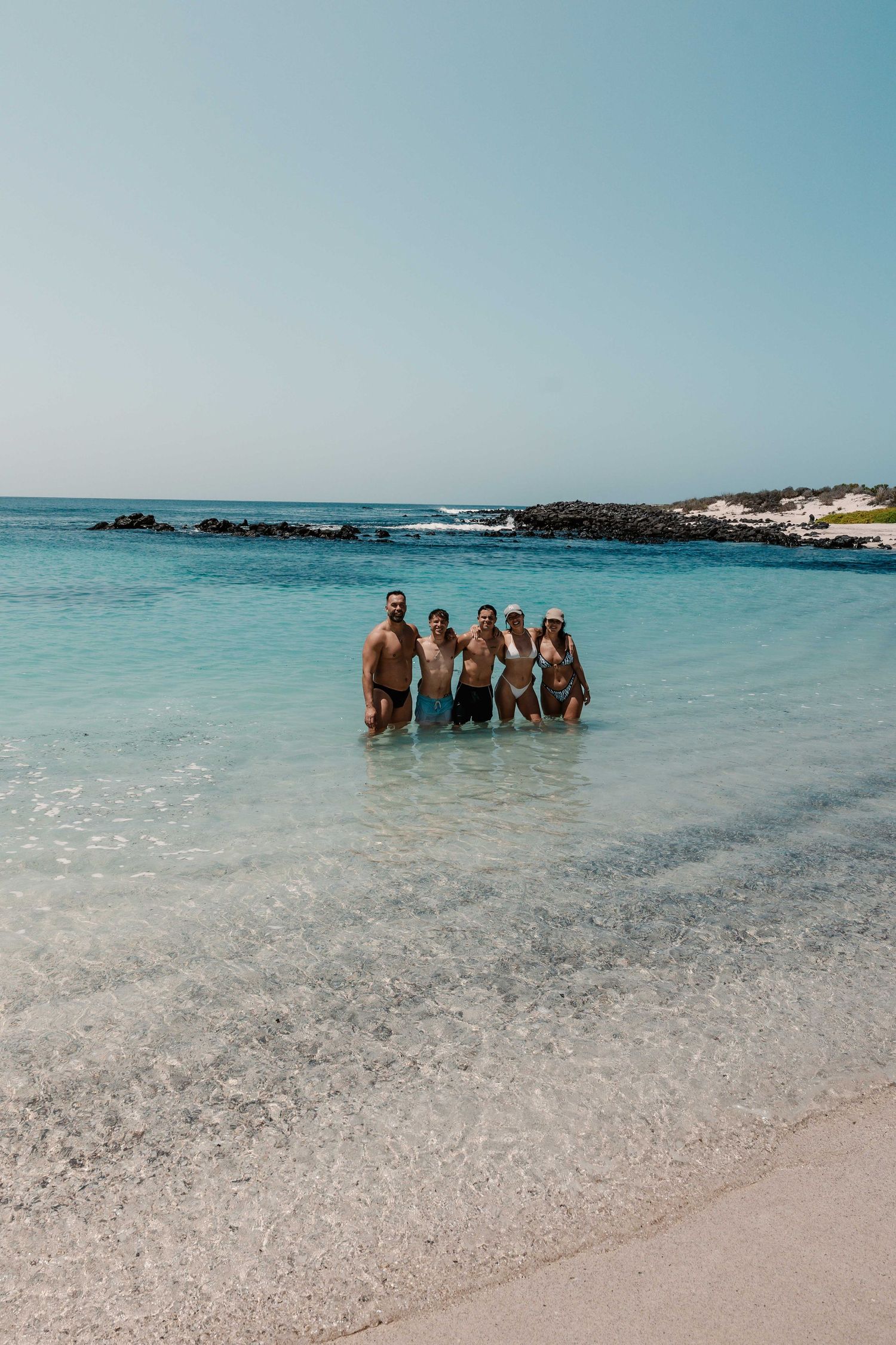 Group enjoying crystal clear turquoise waters at a pristine tropical beach.