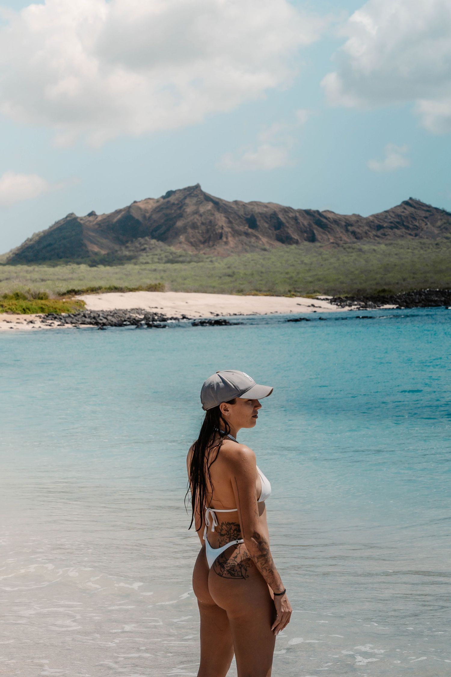 Scenic beach landscape with turquoise waters and rocky mountains under cloudy sky.
